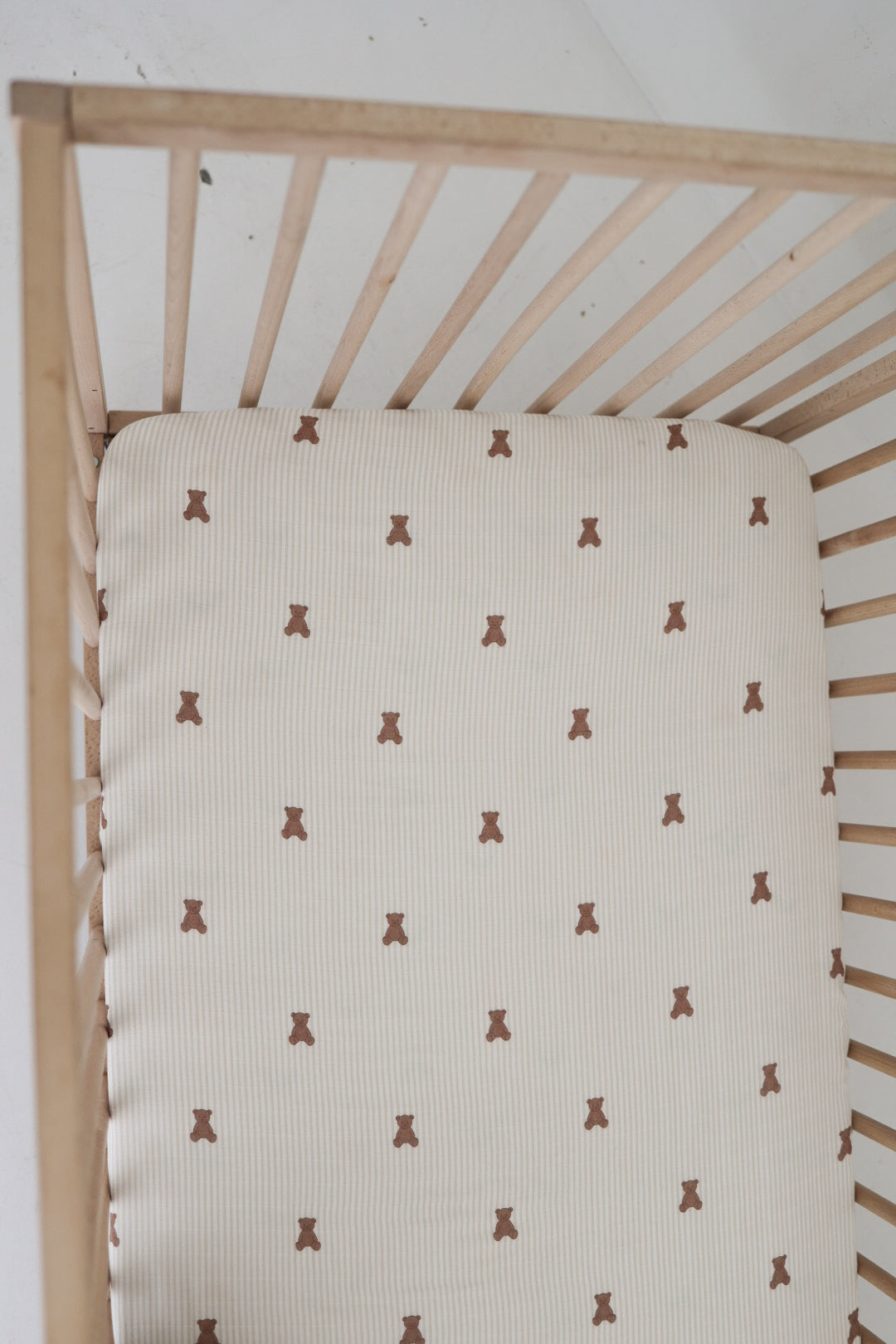 The forever french baby Muslin Crib Sheet | Teddy features a cozy white muslin fabric with a charming small brown teddy bear print, perfect for creating adorable baby bedding.