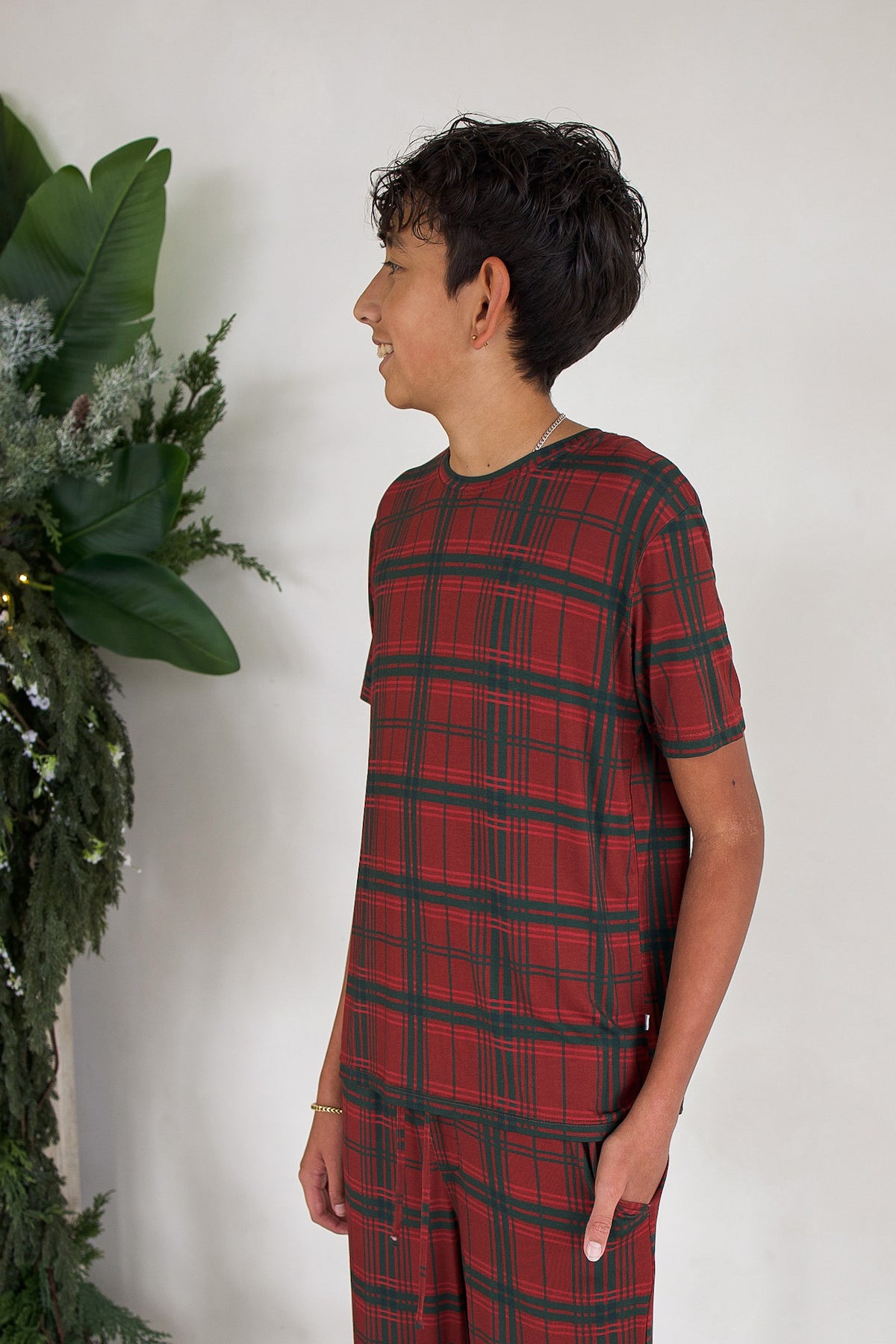 A boy wearing Youth Straight Leg Bamboo Pajamas in Christmas Plaid, featuring a red and green plaid shirt and pants.