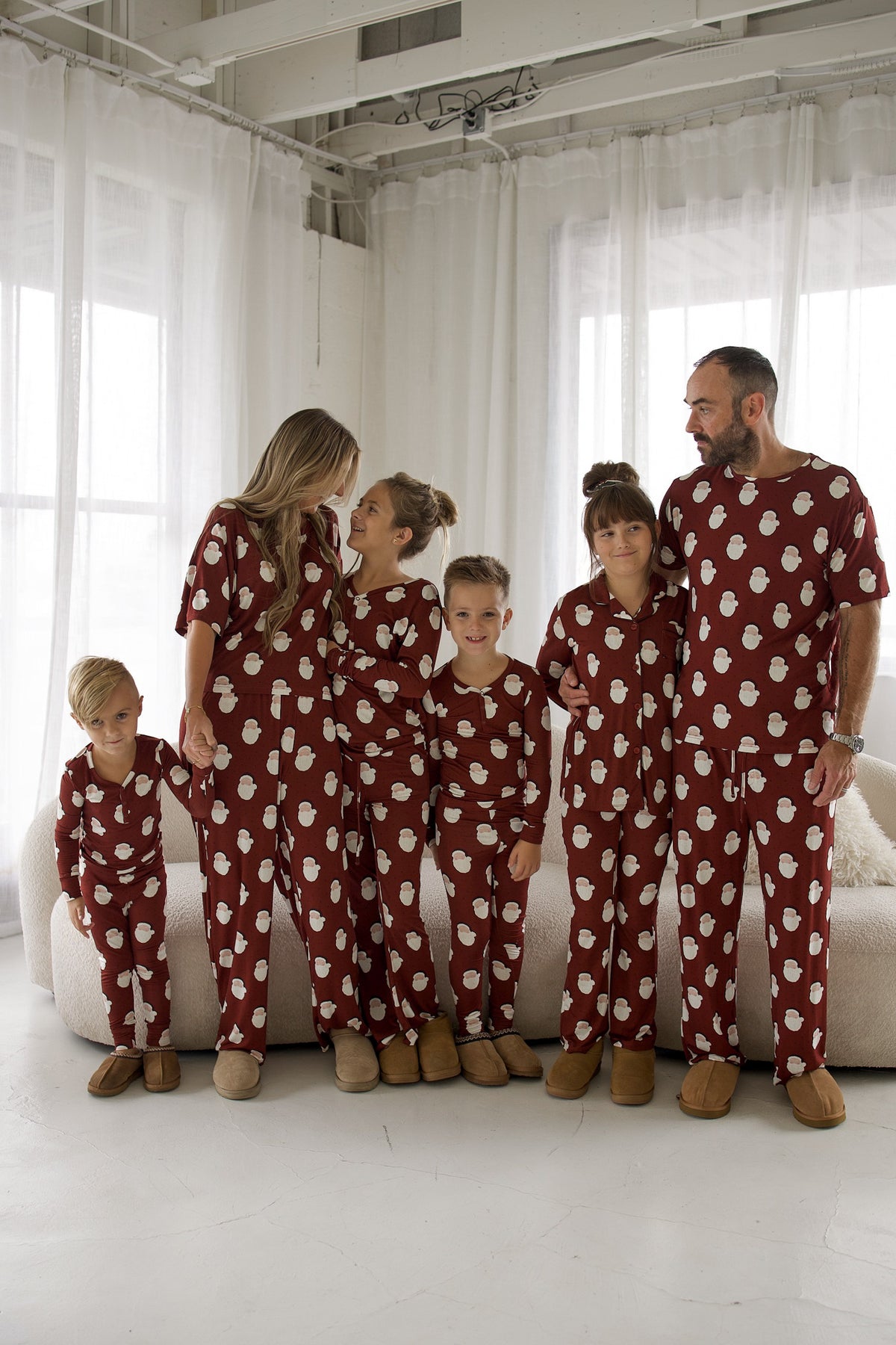 A family of six wearing matching maroon Bamboo Two Piece Pajamas | Vintage Santa with a white Santa print standing in a bright room.