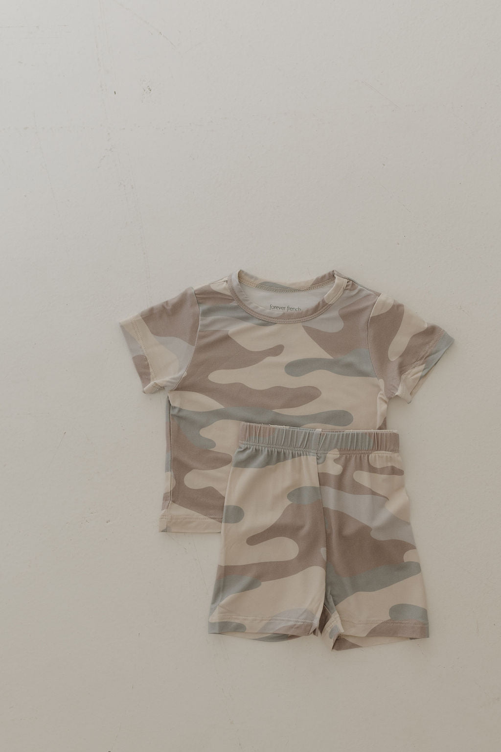 The Bamboo Short Set | Camo by forever french baby, made from breathable hypo-allergenic fabric, includes a brown and beige camouflage-patterned short-sleeve shirt and matching shorts, laid flat on a light surface.
