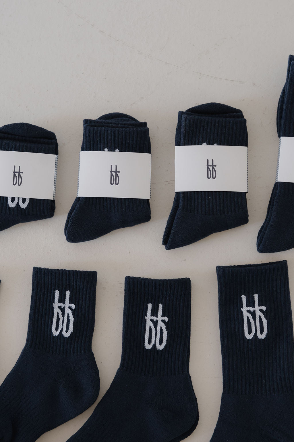 Multiple pairs of ff Crew Socks | Navy from forever french baby, each featuring a white "bb" logo, are displayed on a light surface. Some are folded and wrapped with matching white "bb" logo labels.