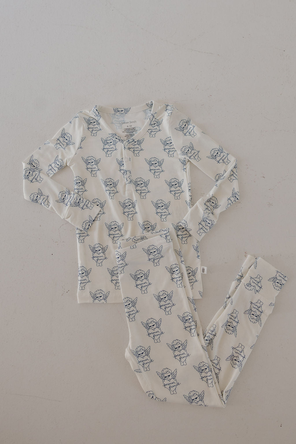 The Bamboo Two Piece Pajamas by forever french baby feature cream-colored, long sleeves and matching pants with a blue bear pattern. Breathable bamboo fabric makes them perfect for cozy nights. Available at ff Los Angeles.