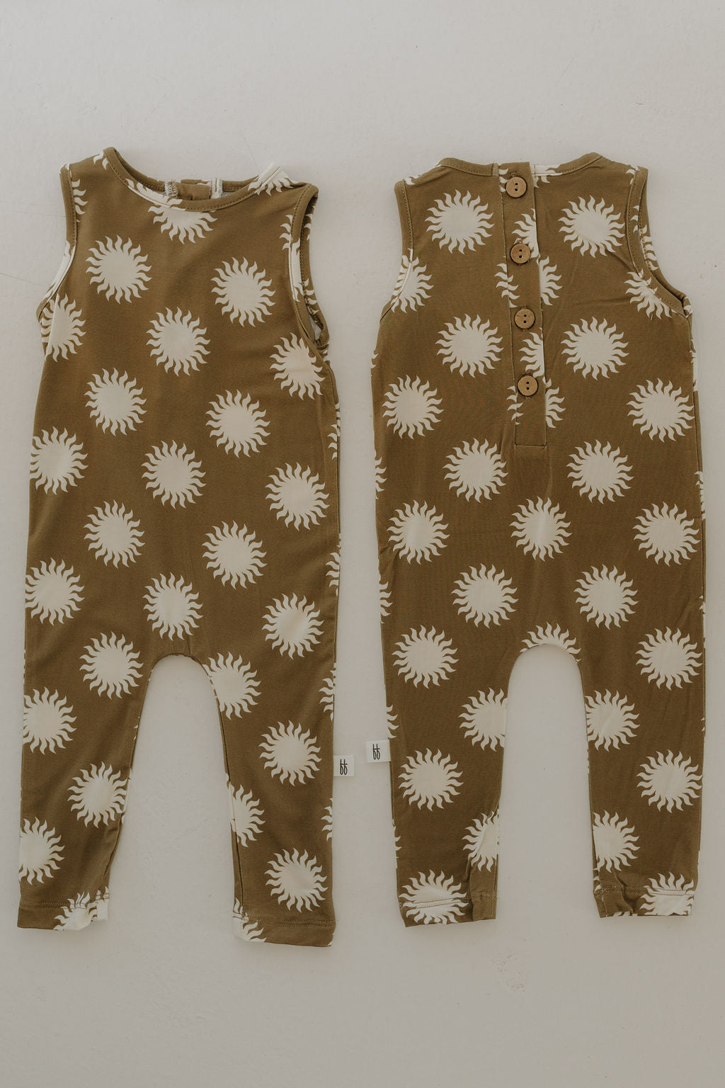 The Harem Bamboo Romper | Sol by forever french baby features two sleeveless brown rompers made from breathable bamboo fabric with a white sun pattern. Flat front and back views on a neutral background showcase back buttons for easy wearing.