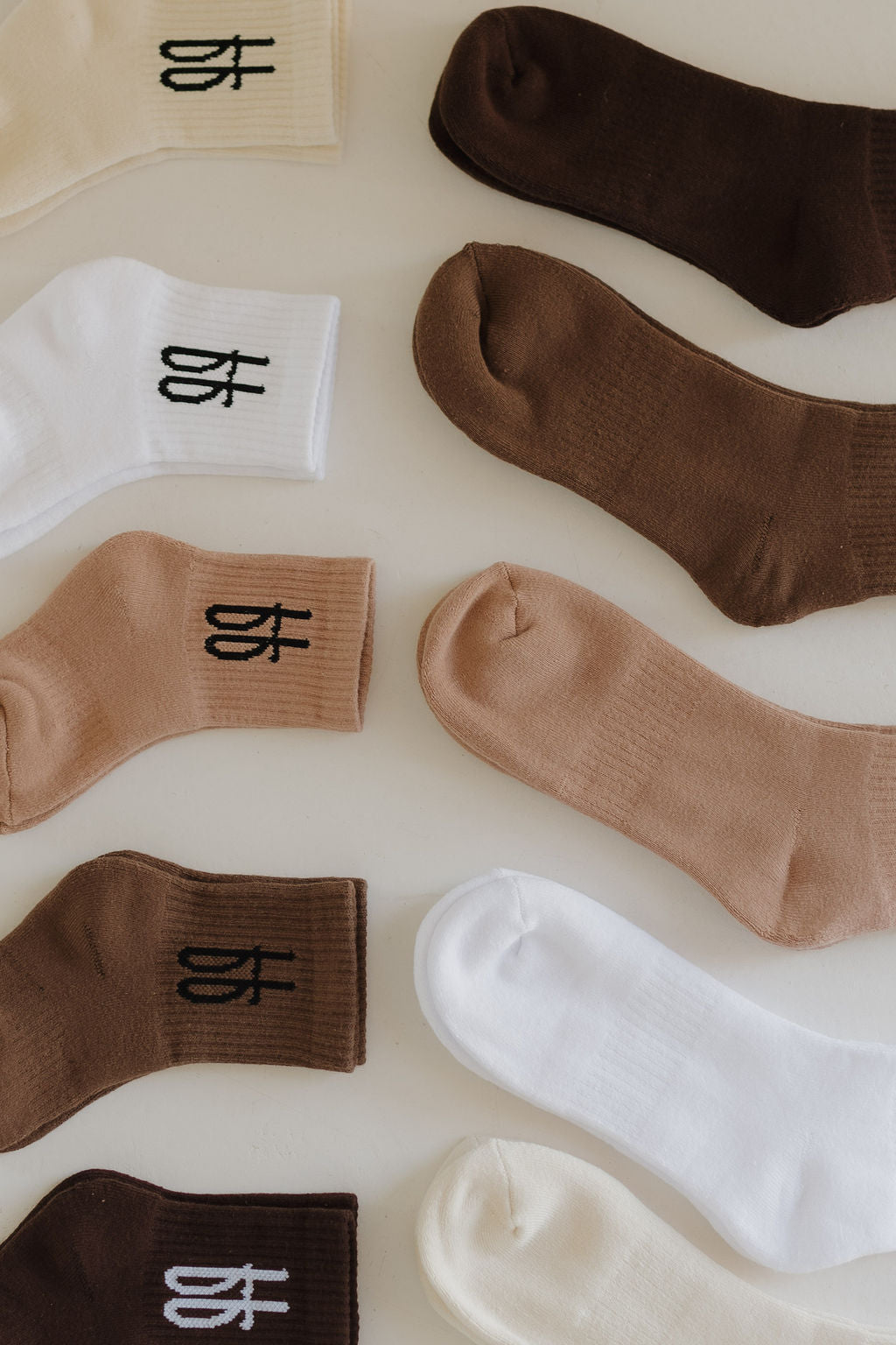 A variety of ff Crew Socks | Cocoa by forever french baby are displayed in rows on a light surface, featuring shades of brown, beige, and white. Each sock showcases a small logo near the top, exuding timeless elegance suitable for the entire family.