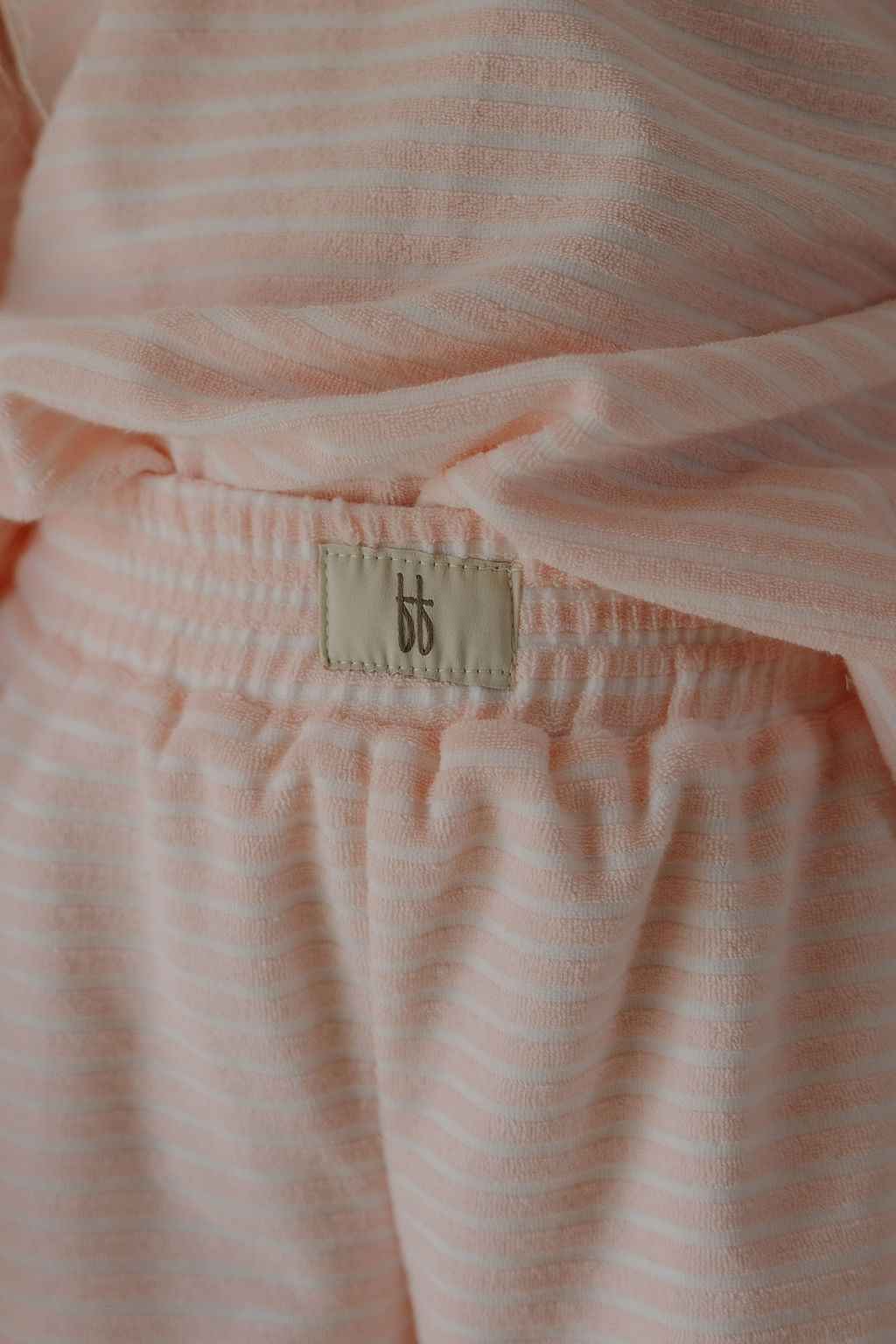 Close-up of the Child Terry Short Set | Cotton Candy by forever french baby, featuring light pink and white stripes, elastic waistband, and a beige "bb" logo label—perfect for cozy family moments.
