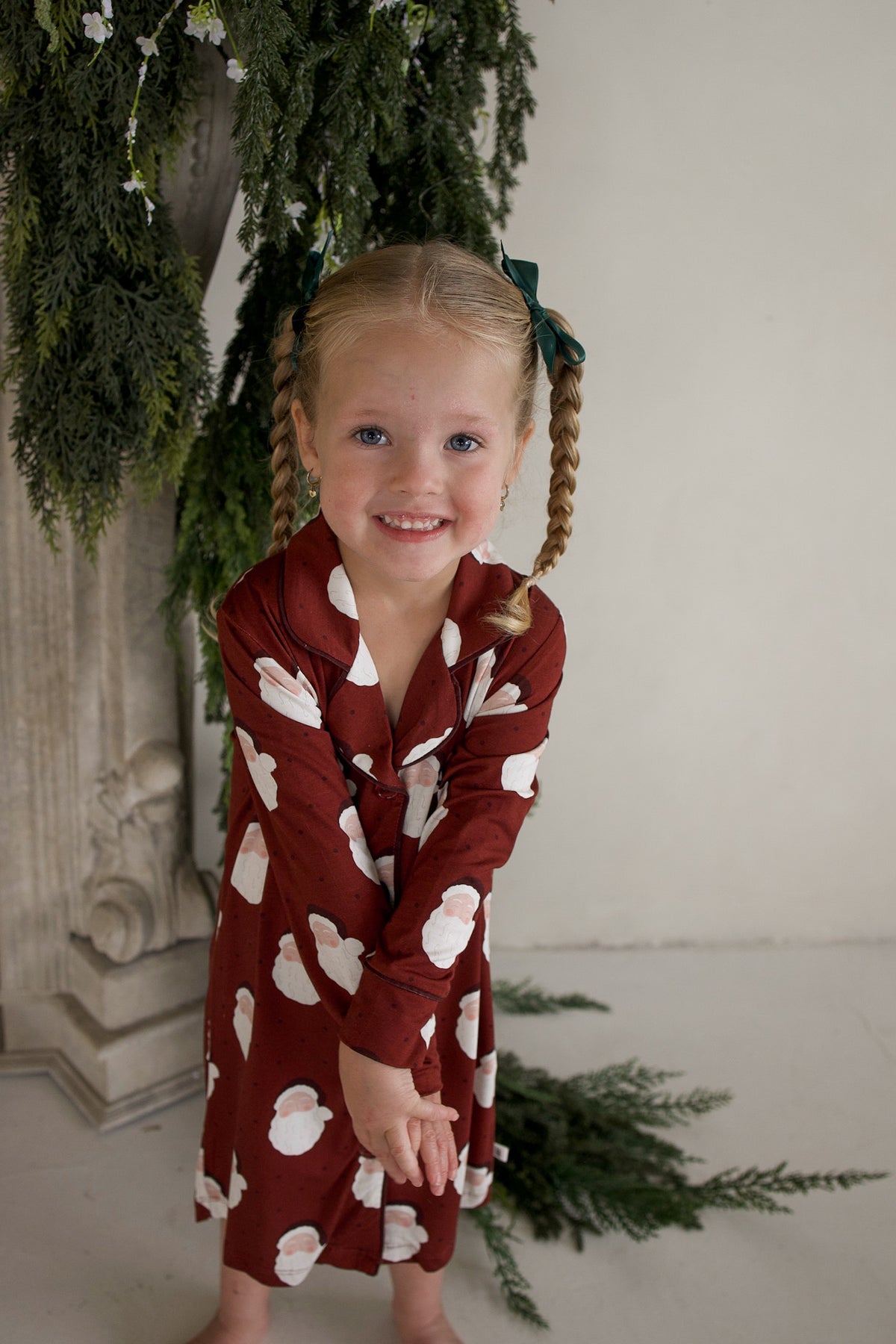 A young girl wearing a long-sleeved, hypo-allergenic forever french baby Bamboo Sleeping Dress | Vintage Santa with a vintage Santa Claus pattern.