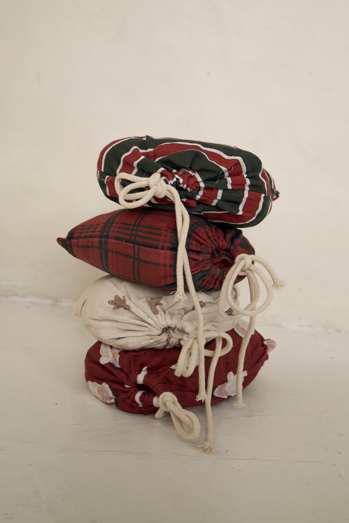 Four Muslin Crib Sheet | Christmas Plaid drawstring fabric bags stacked vertically.