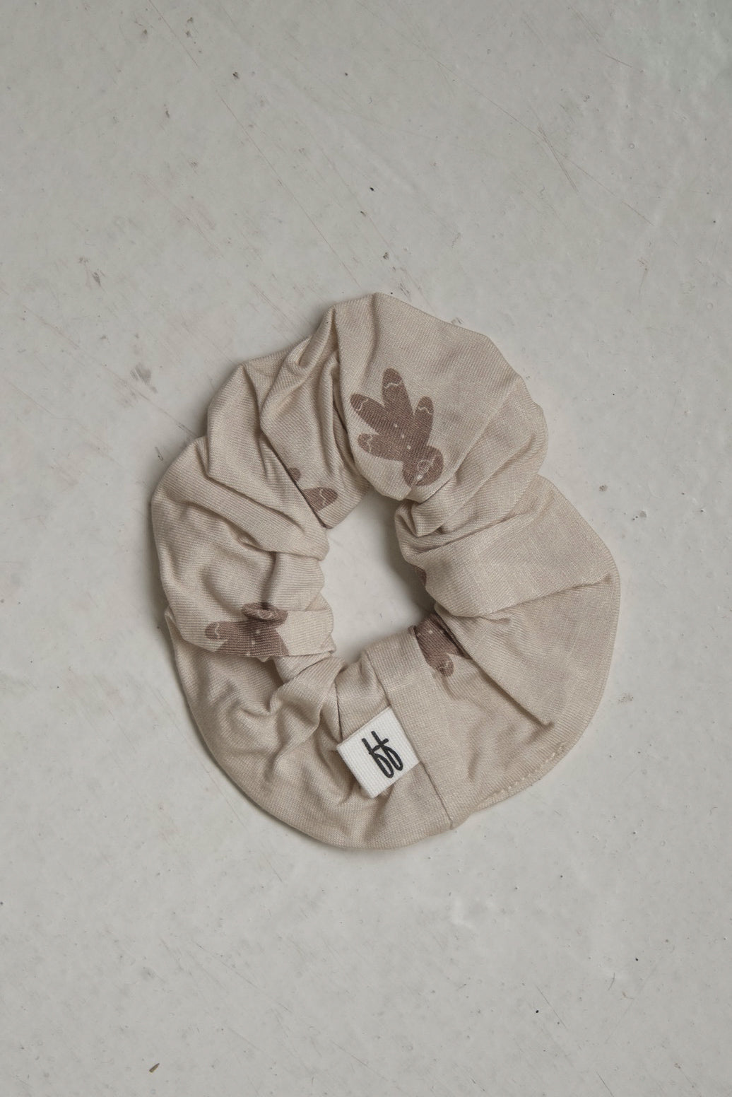 Beige bamboo Scrunchie | Gingersnap featuring a brown gingersnap print gingerbread man pattern and a small white forever french baby brand tag.