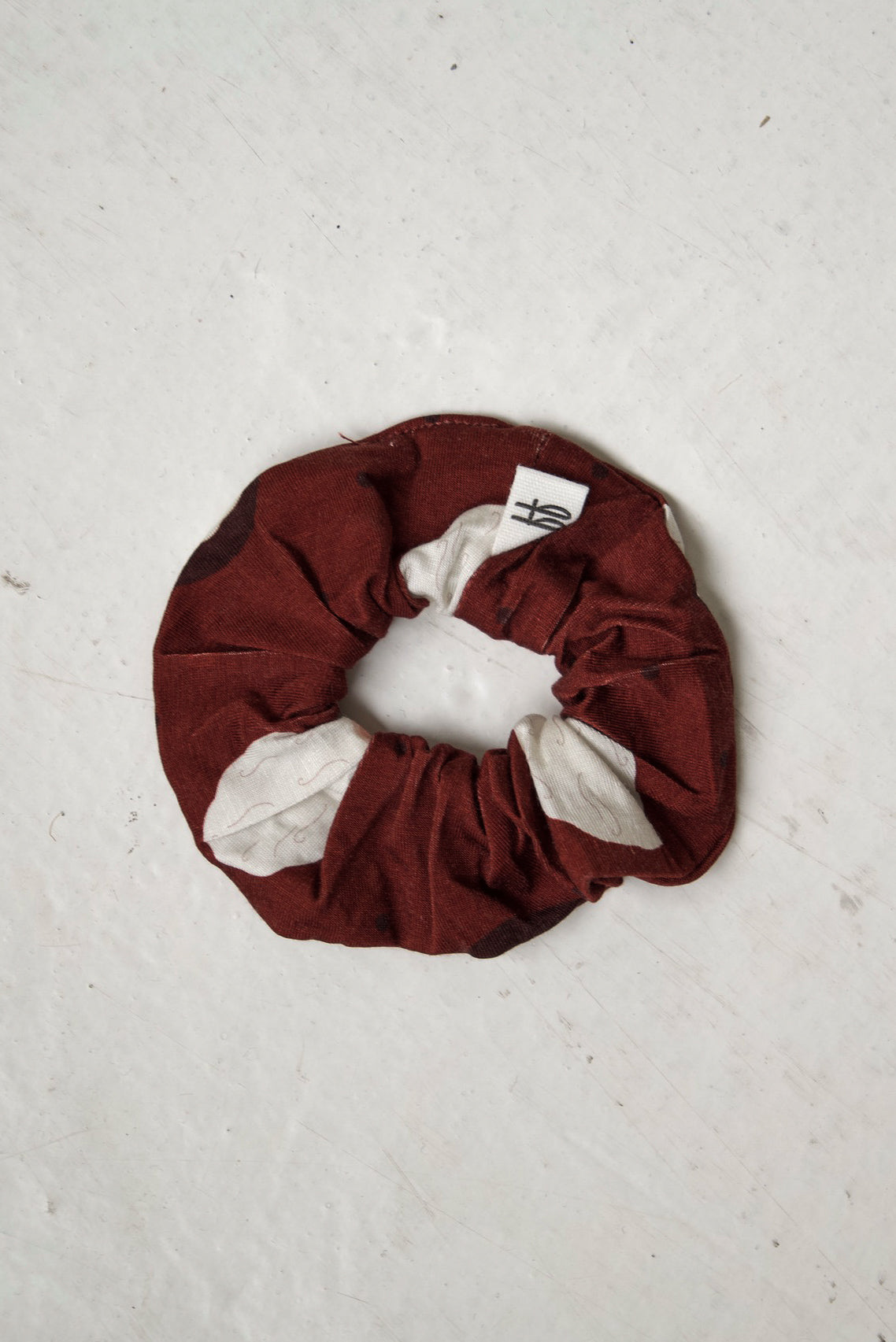 A maroon Scrunchie | Vintage Santa from forever french baby featuring a repeating pattern of white vintage Santa Claus faces.