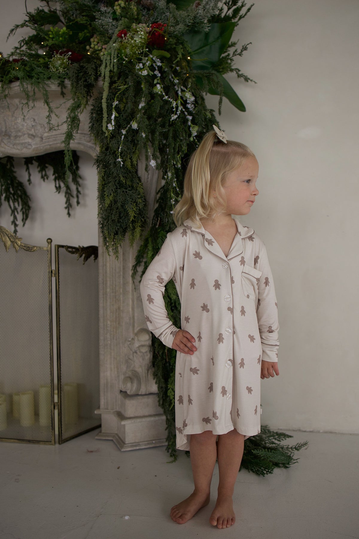 A young girl wears the Bamboo Sleeping Dress | Gingersnap by forever french baby—breathable kids clothing with a sweet brown gingerbread man print, perfect for cozy dreams.