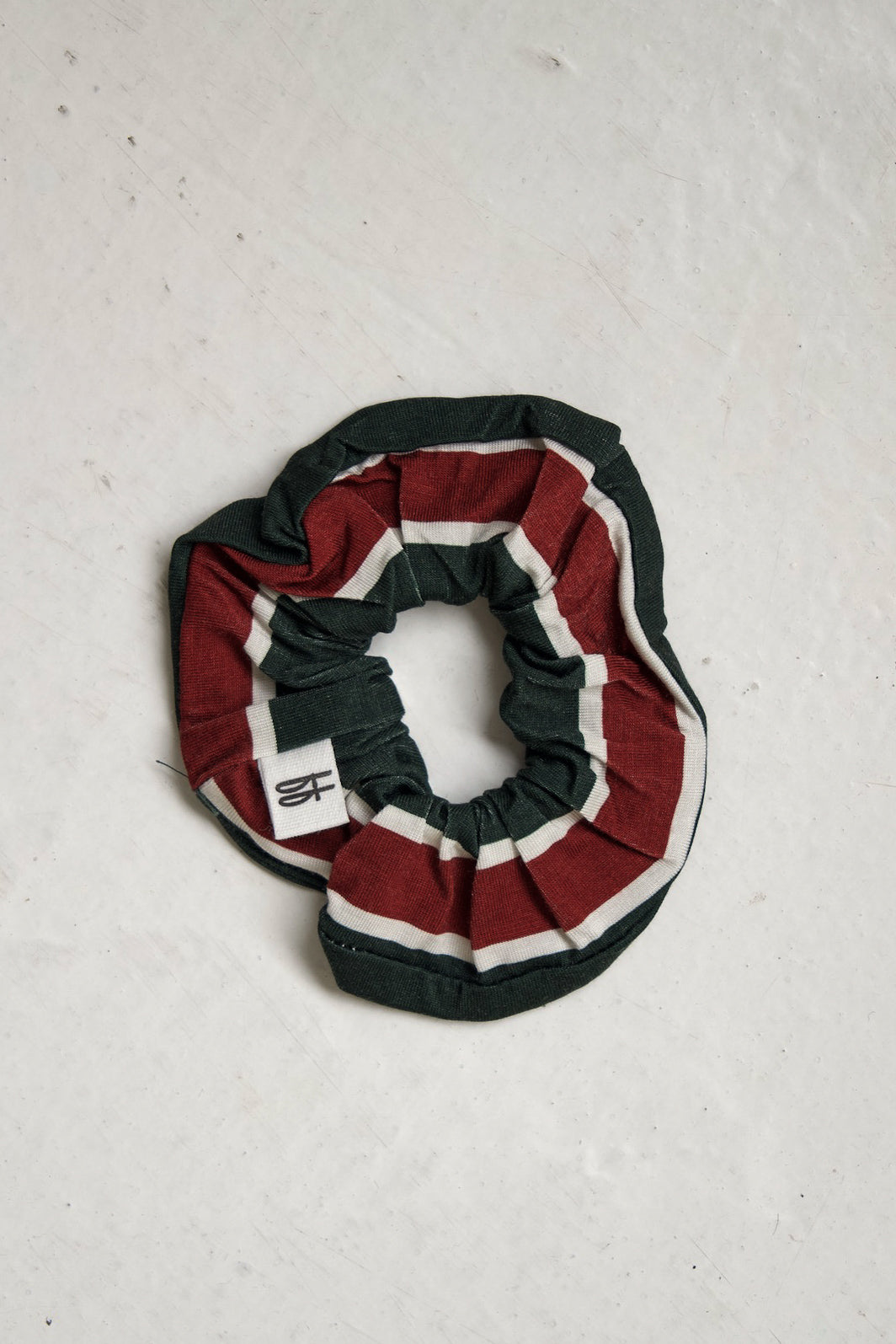 Scrunchie | Holiday Stripe by forever french baby in bamboo fabric featuring dark green, red, and white holiday stripes and a small white brand tag.
