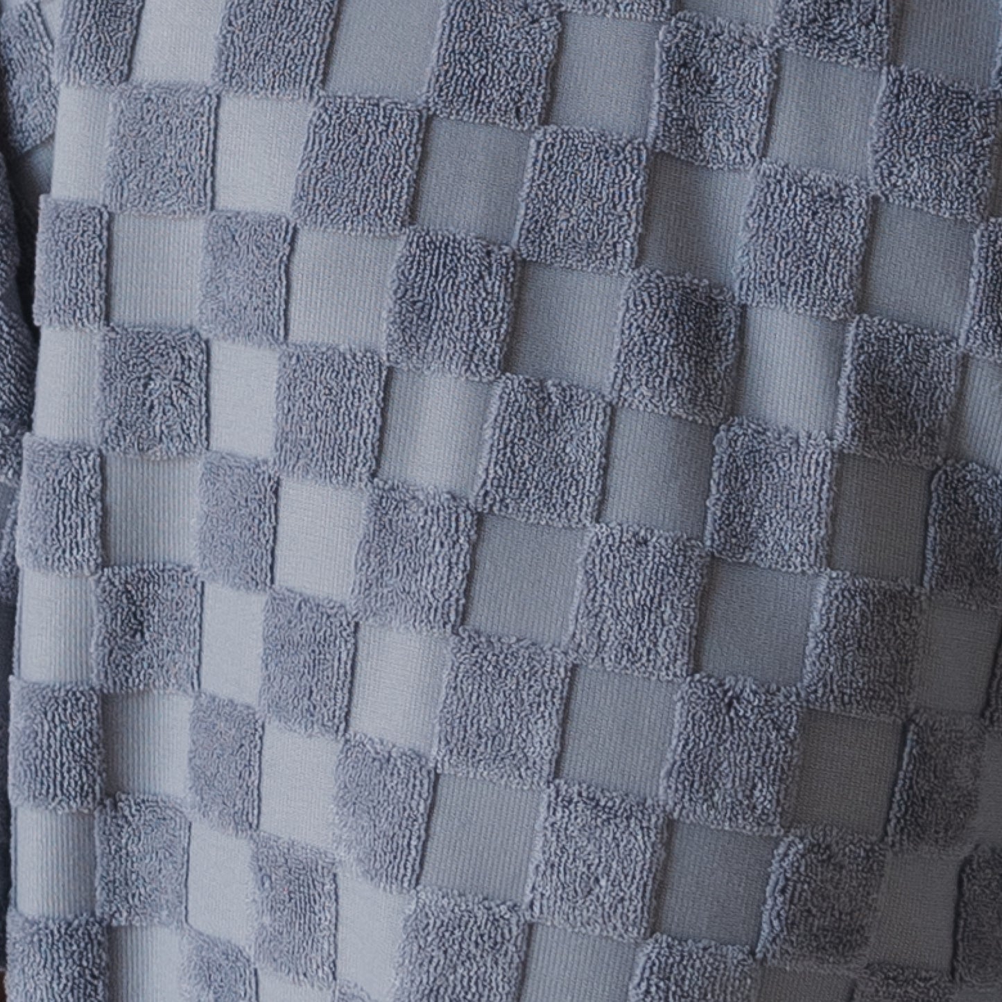 Close-up of the forever french baby Terry T-Shirt Romper | Tradewinds fabric, featuring a raised checkerboard pattern in soft gray tones. The texture blends smooth and plush for a cozy, three-dimensional feel—ideal for comfort.