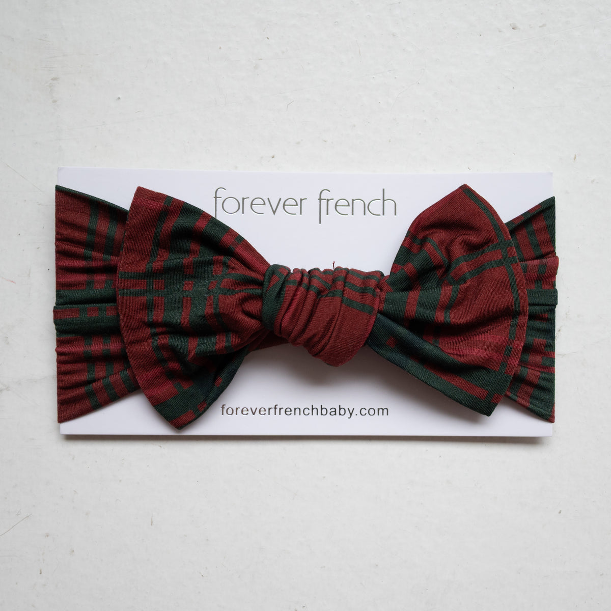A forever french baby Bamboo Head Wrap | Christmas Plaid in a red and green bow-style design on a display card.