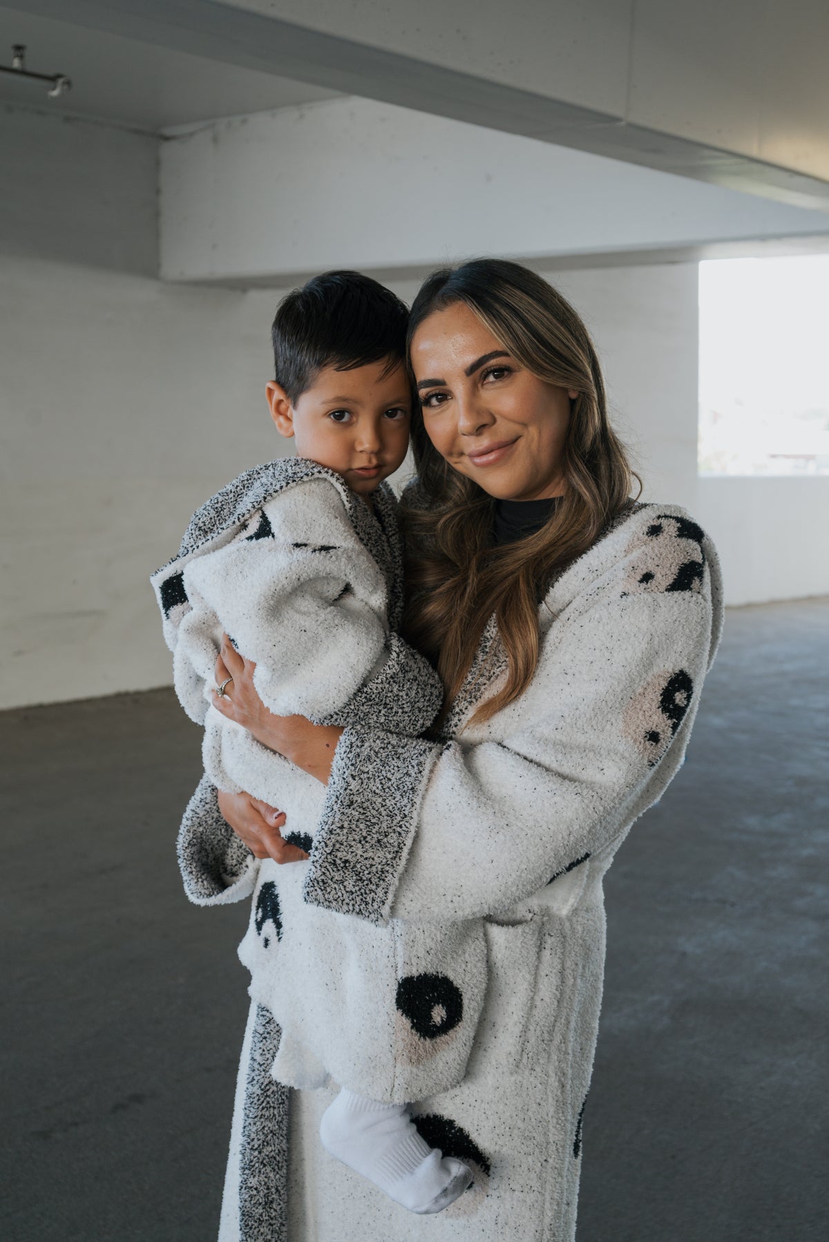 A woman and a young boy wearing matching Children’s Robe | Yin Yang white and black patterned hooded robes made of microfiber feather yarn.
