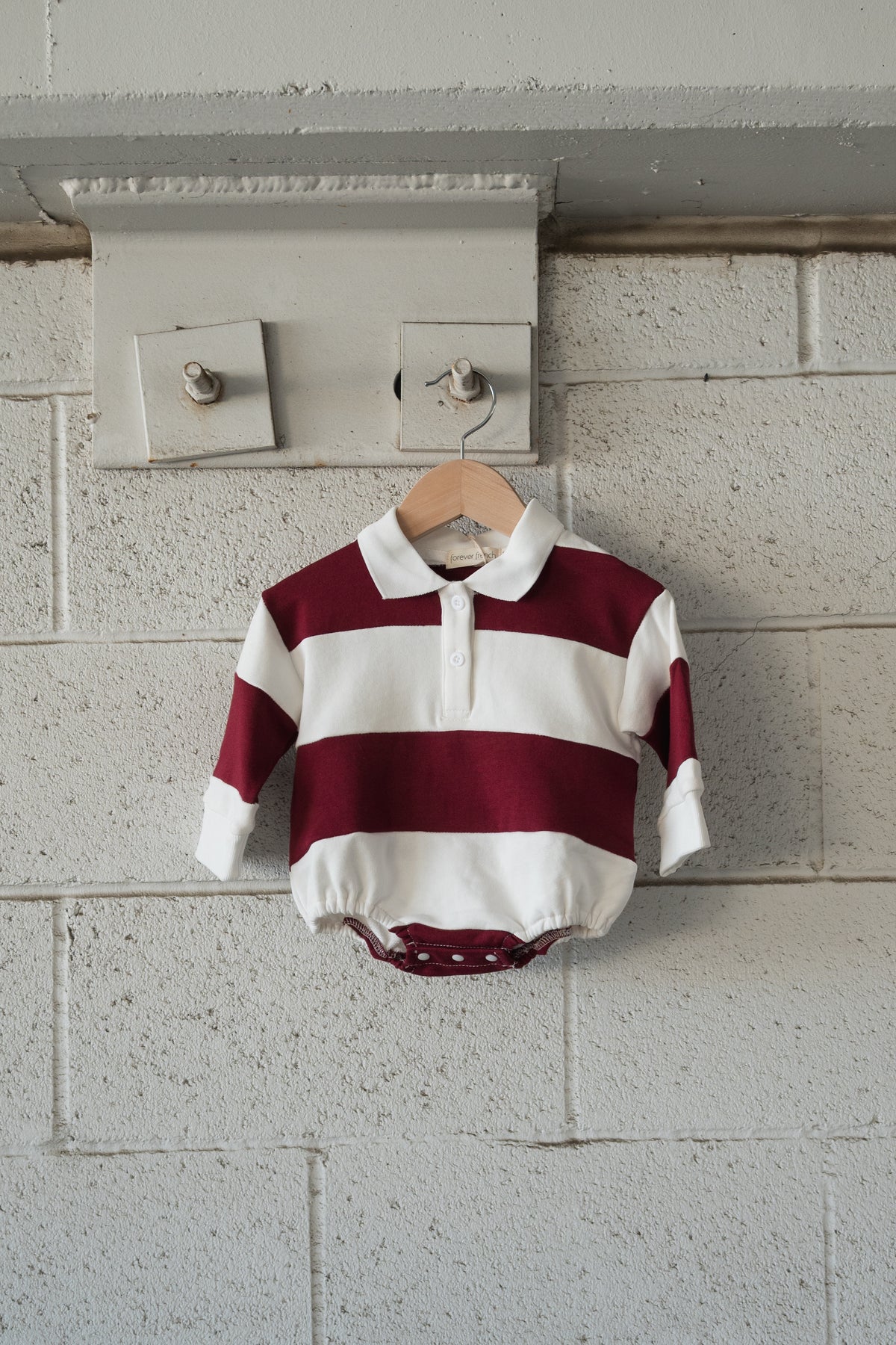 Forever French Baby Rugby Sweatshirt Romper in Deep Cranberry, a long-sleeved baby romper with wide cranberry and white horizontal stripes, a polo collar, and bottom snaps.