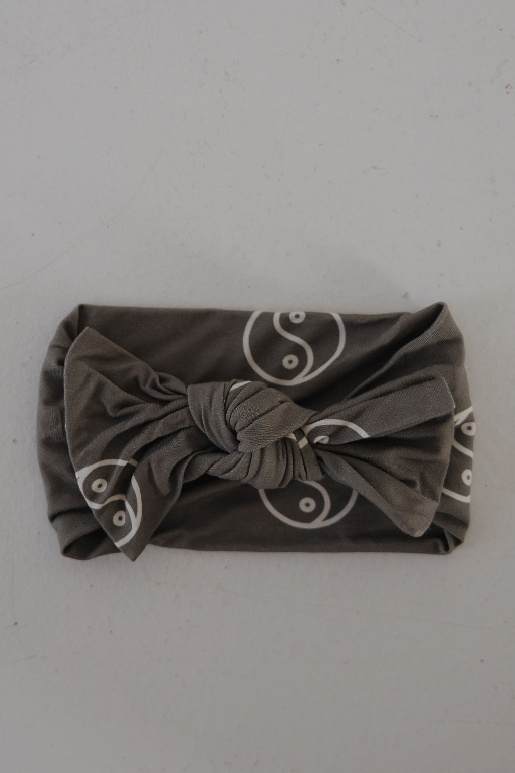 The Bamboo Head Wrap | Sage Yin Yang by forever french baby features a sage fabric with white yin-yang pattern and a twisted knot center, shown on a light textured surface. Adds cute style to any outfit.