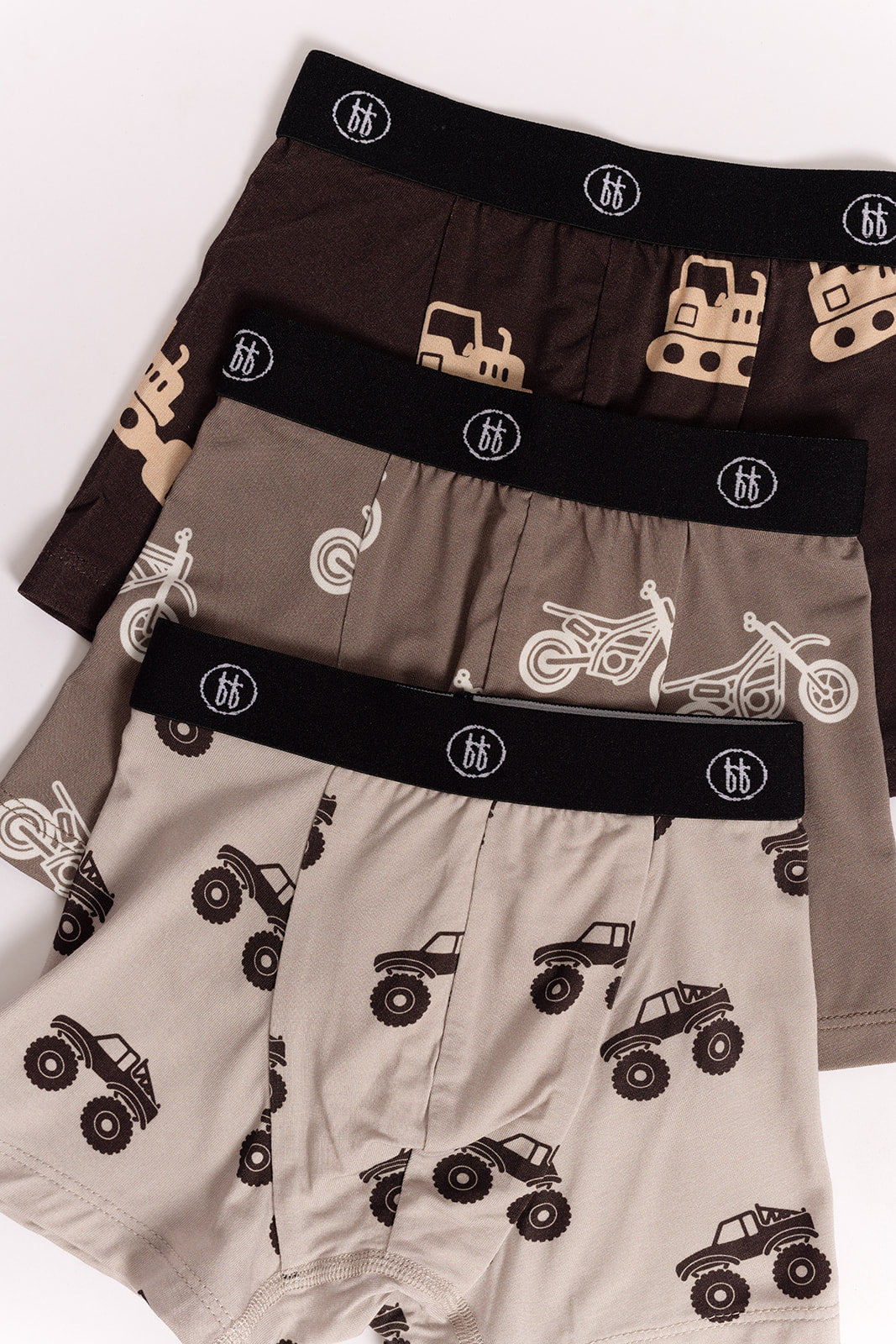 The forever french baby Bamboo Boxers (3 Pack) include hypoallergenic boys’ underwear with black logo waistbands and fun prints: construction vehicles on brown, motorcycles on taupe, and monster trucks on beige.