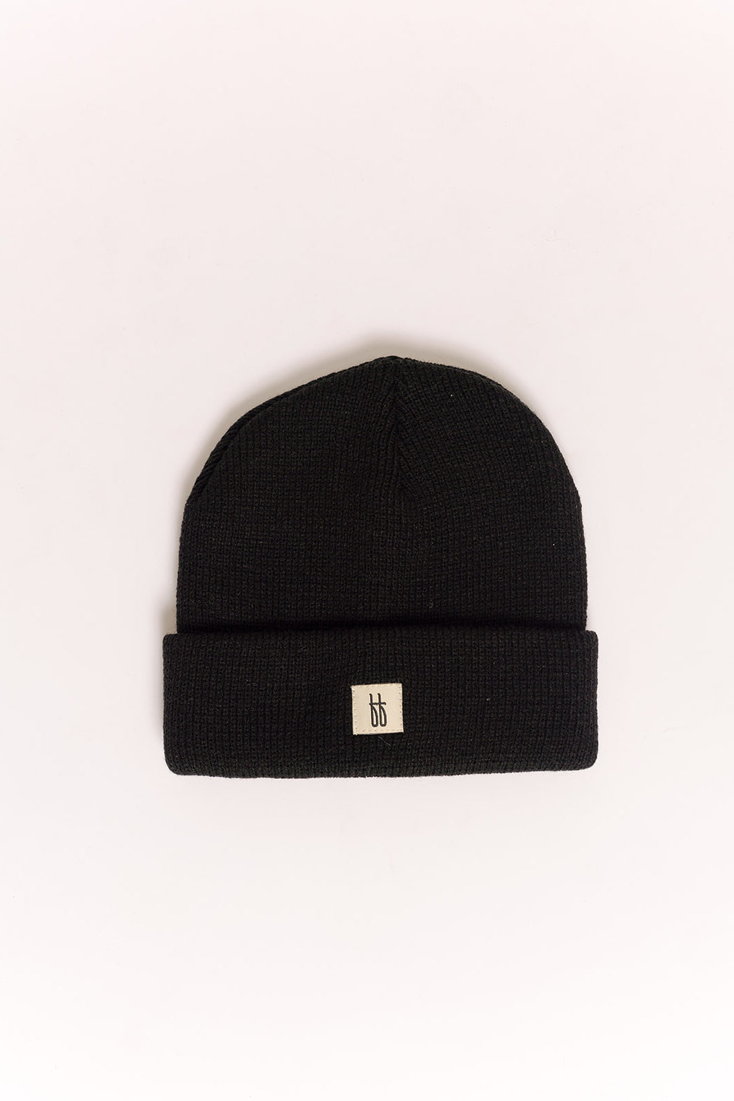 The forever french baby ff Knit Beanie | Black features a folded brim and a small white patch with a minimalist black logo on the front, shown against a plain white background.