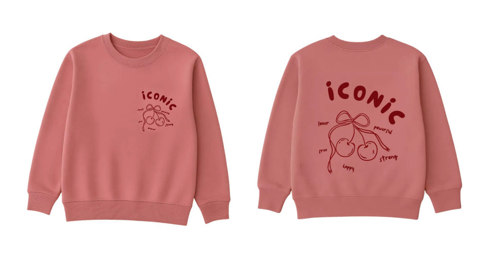 The Minty Cherries Women's Sweatshirt | Iconic (Pre-Order) is a pink crewneck with "ICONIC" and cherries on the front, plus a large cherry and uplifting words like "powerful," "happy," and "love" on the back.