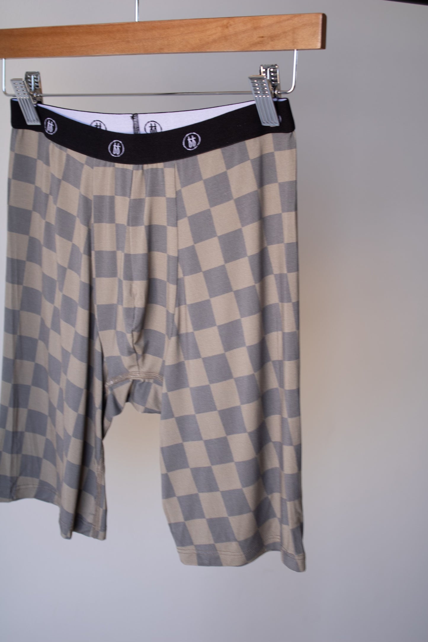 Forever french baby Men's Bamboo Boxers (3 Pack) in checkerboard and faded brown patterns, loose-fitting, knee-length with a black elastic waistband and white logo, shown hanging on a wooden hanger against a plain background.