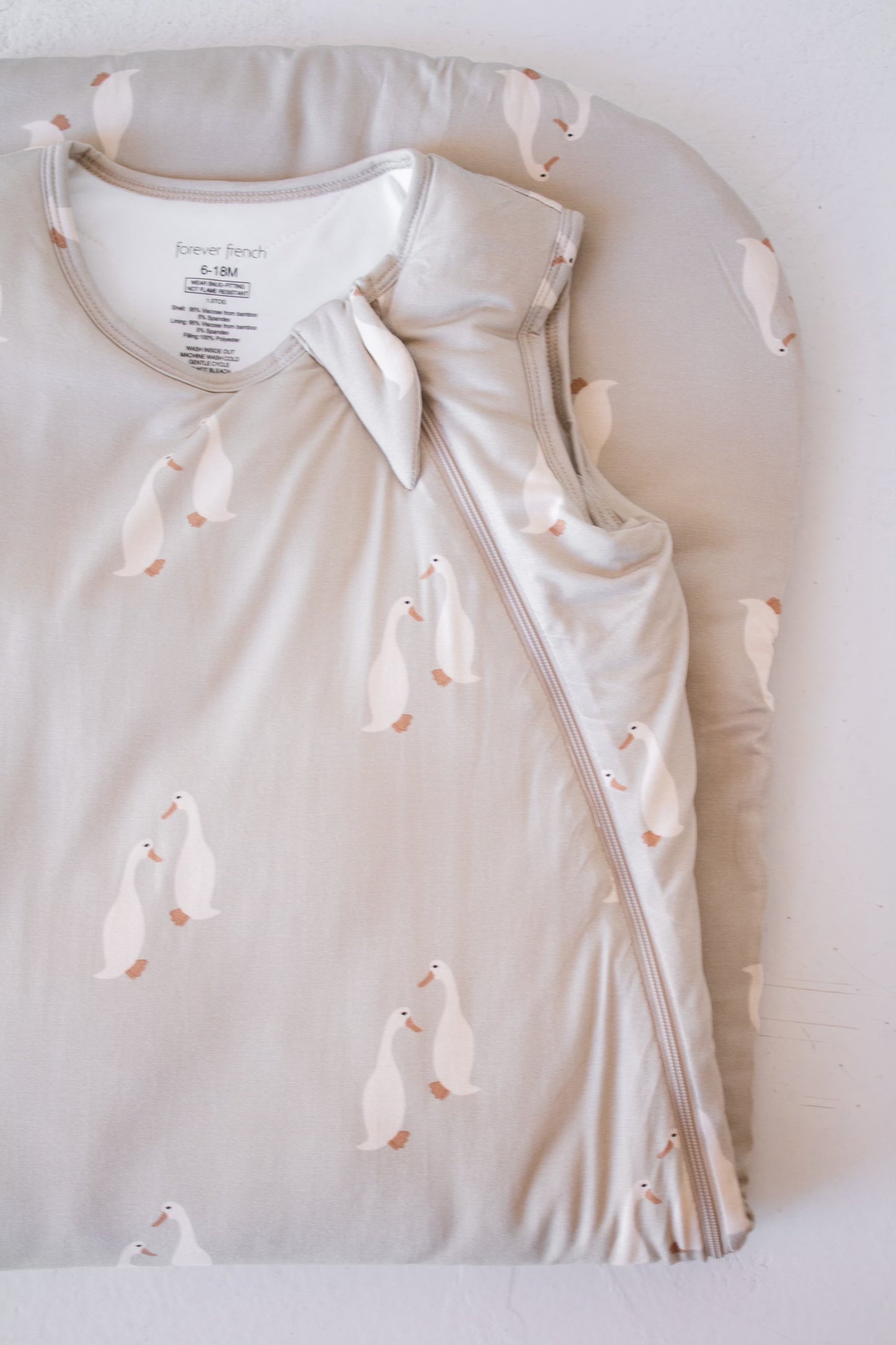 The forever french baby Bamboo Sleep Sack | Silly Goose features a soft light gray fabric with white goose print, a zipper, and comes folded on a matching pad—an ideal breathable blanket for restful nights.