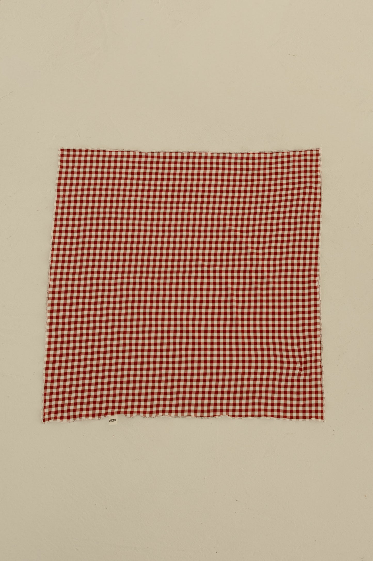 The Bamboo Bandana | Red Gingham by forever french baby, crafted from soft fabric, is displayed flat on a plain, light-colored surface.