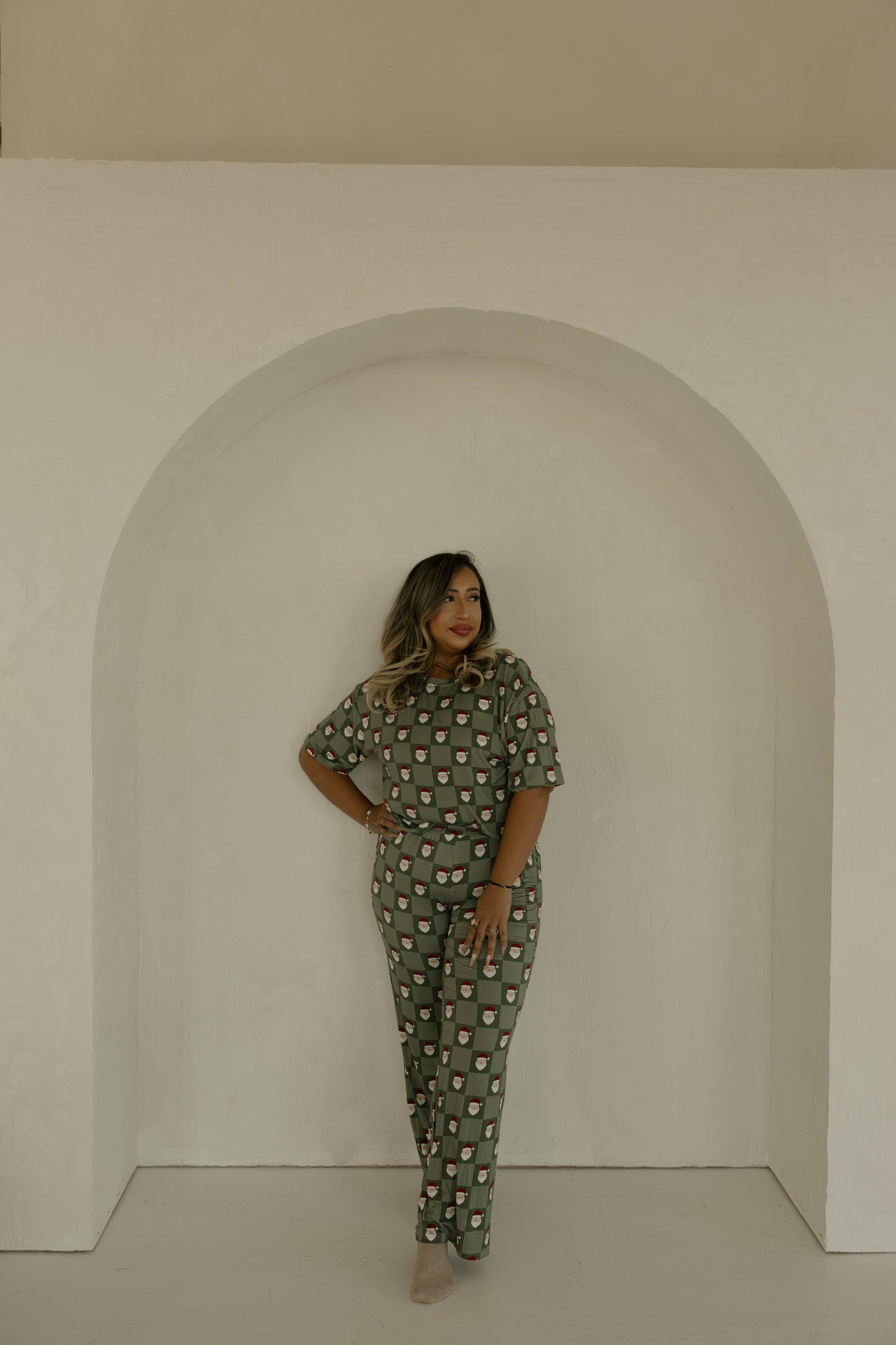 A woman stands confidently in front of a white arch, wearing the Women's Boxy Tee Lounge Set in Santa Checkerboard by forever french baby. She has long hair, red lipstick, and looks to the side with one hand on her hip.