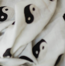 A close-up photo of the Muslin Swaddle | Black & White Yin Yang by forever french baby, showcasing its black and white yin-yang symbols. Perfect for a modern nursery, this soft and slightly crumpled swaddle creates gentle folds and shadows.