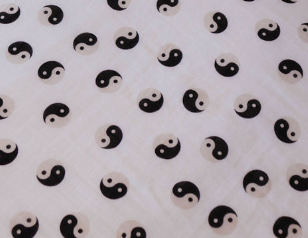 The Muslin Quilt | Black & White Yin Yang / Stripe by forever french baby features a white fabric made from 100% muslin cotton, adorned with evenly spaced, alternating black and white yin-yang symbols. The neat diagonal rows of this pattern create a uniform and orderly appearance across the surface, making it ideal for a reversible quilt.