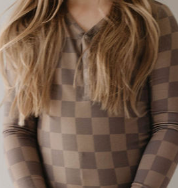 A person with long blonde hair is seen wearing the "Bamboo Two Piece Pajama" in Faded Brown Checkerboard by forever french baby. The image is cropped to show only the torso and part of the head.