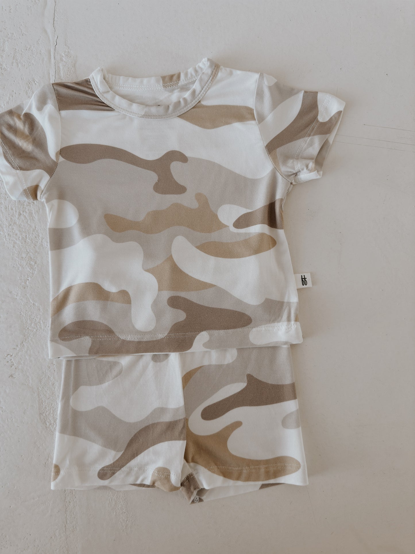 The Bamboo Short Set | Camo 2.0 by forever french baby features a beige, tan, and white camo pattern in breathable fabric, shown laid flat on a light textured surface.