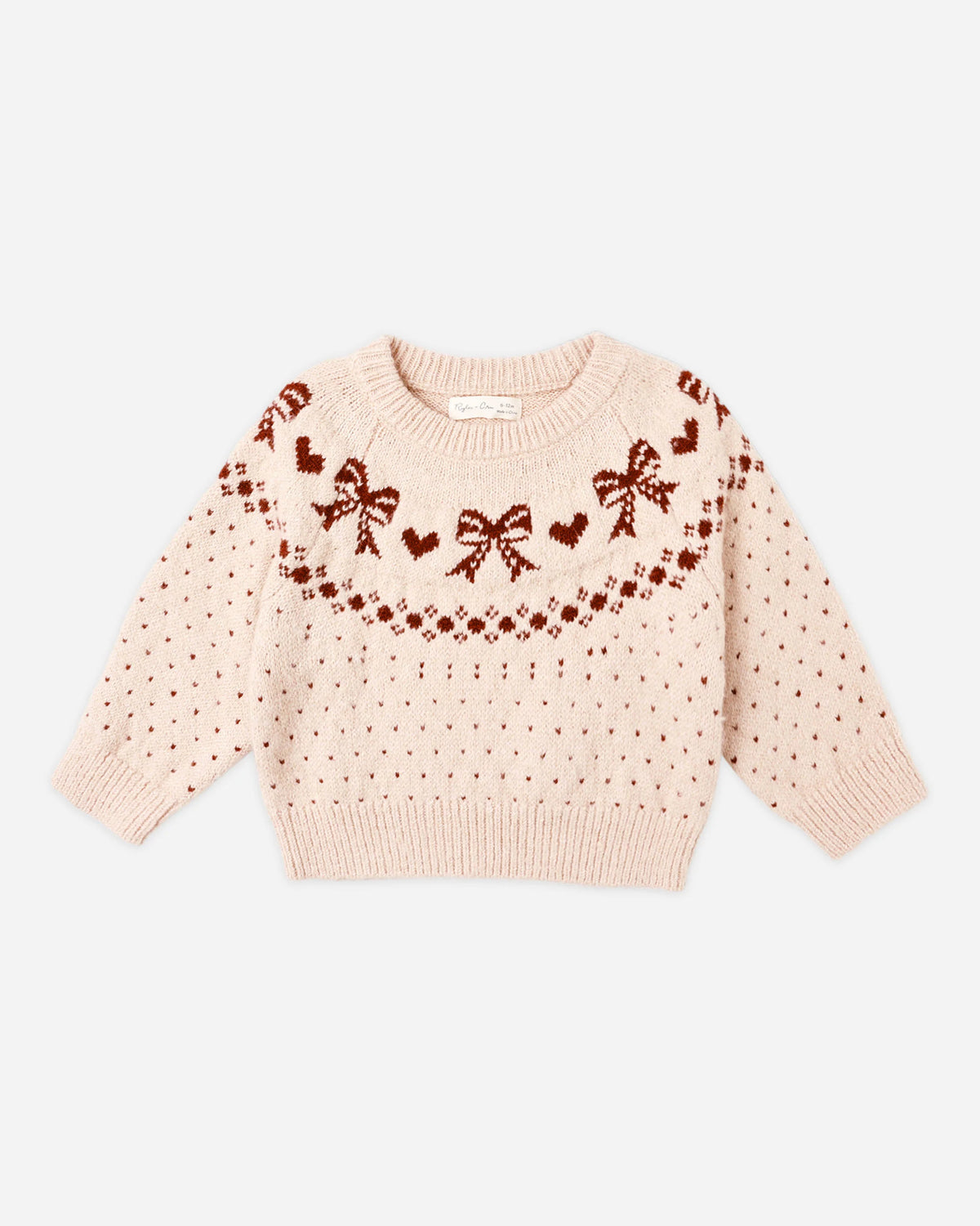 The Fair Isle Sweater | Bows by Rylee + Cru is a light pink cozy knit sweater adorned with a charming bow motif, red hearts, and small dot patterns across the chest and sleeves. It features a round neckline with ribbed cuffs and hem, shown laid flat on a white background.
