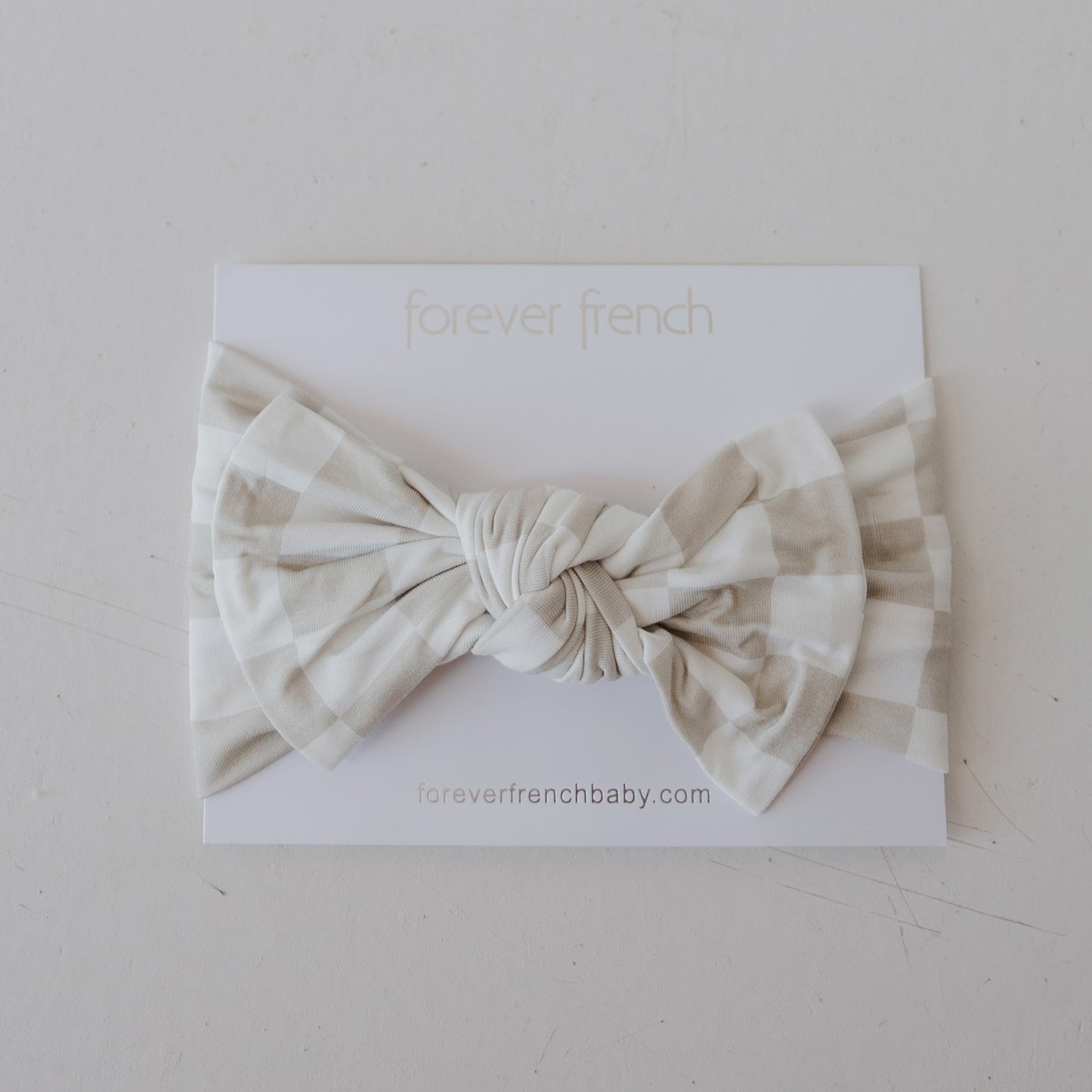 The Bamboo Head Wrap | Checkerboard from forever french baby is shown in beige and white on a white card labeled "forever french," with "foreverfrenchbaby.com" printed below.