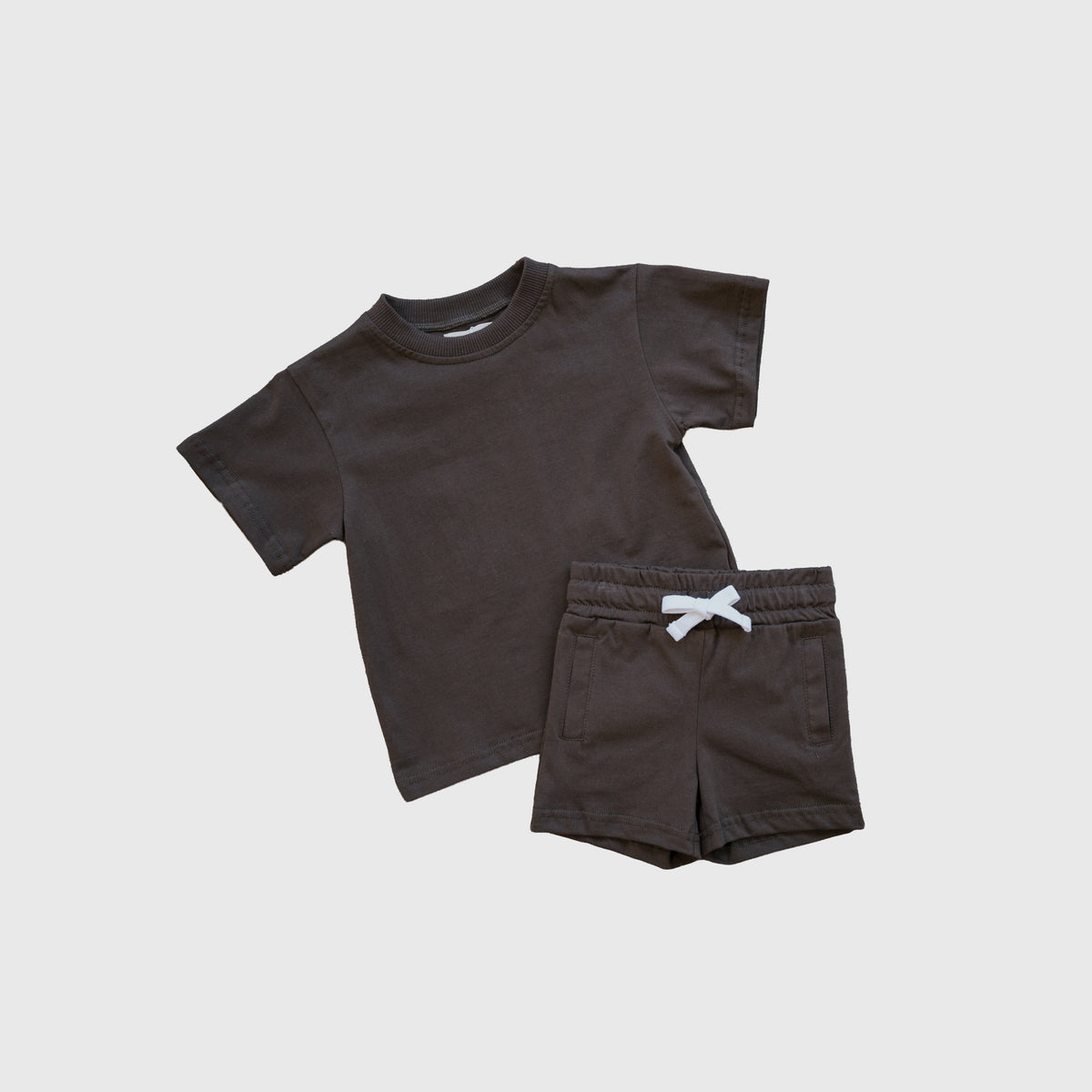Introducing the forever french baby Child Short Set | Espresso: a 100% cotton everyday set for kids, featuring a dark brown short-sleeve t-shirt and coordinating shorts with a white drawstring. Laid flat on a light background, this comfortable ensemble is perfect for play and daily adventures.