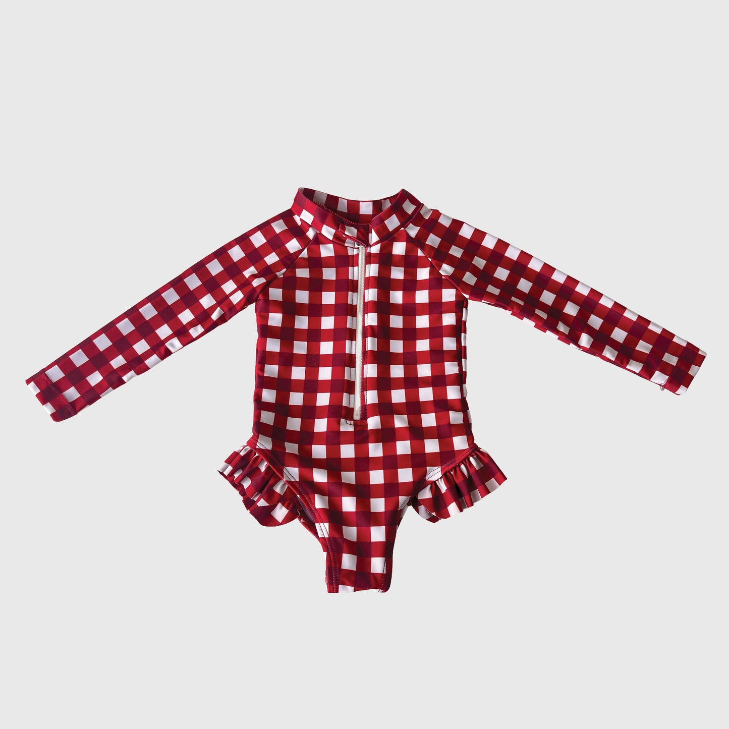 The Girl's Long Sleeve Swimsuit in Scarlet Gingham from forever french baby features a red and white plaid print, front zipper, and ruffle hip details—perfect summer swimwear, shown on a plain white background.