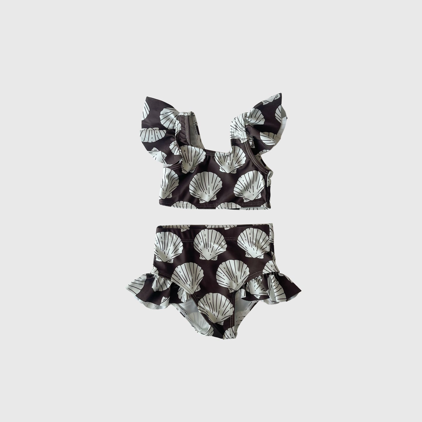 The Girl's Two Piece Swimsuit | Seashells by forever french baby features ruffled sleeves and high-waisted bottoms with a black and white seashell print—stylish kids' swimwear perfect for summer fun.