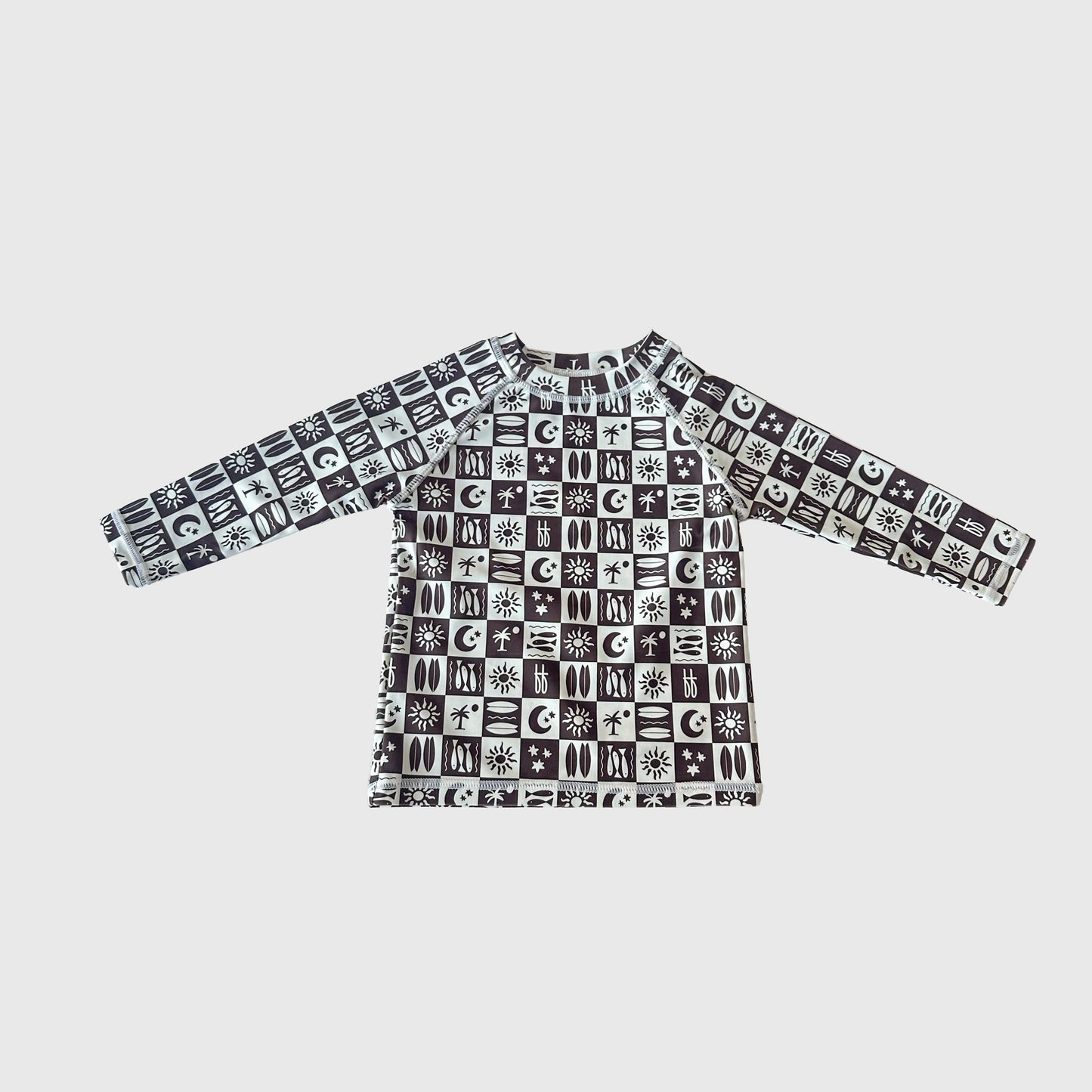The "Child Rash Guard | Summer Check" by forever french baby is a long-sleeve, black-and-white geometric rash guard with sun, moon, and star symbols—perfect for active kids on summer days and shown on a plain light background.