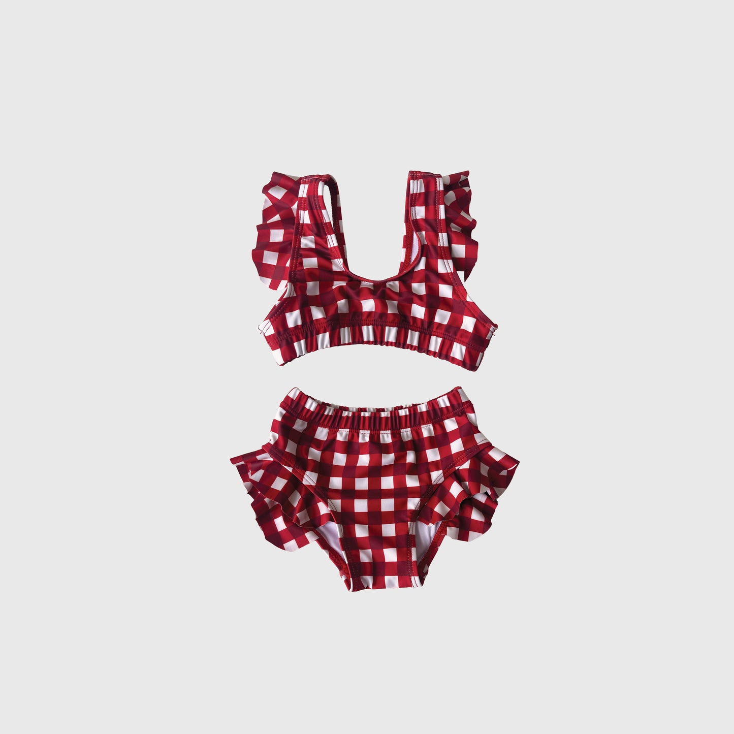 The Girl's Two Piece Swimsuit in scarlet gingham by forever french baby features ruffled shoulder straps on the top and ruffled sides on the bottom, shown against a plain light background.