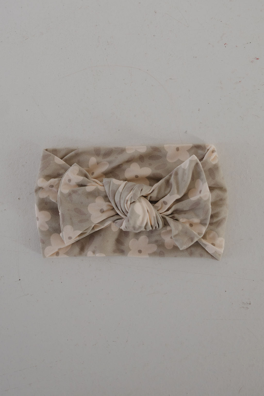 The forever french baby Bamboo Head Wrap | French Gray Floral is a soft, light gray bamboo headband with a large knotted bow and white flower pattern, shown laid flat on a plain light surface.