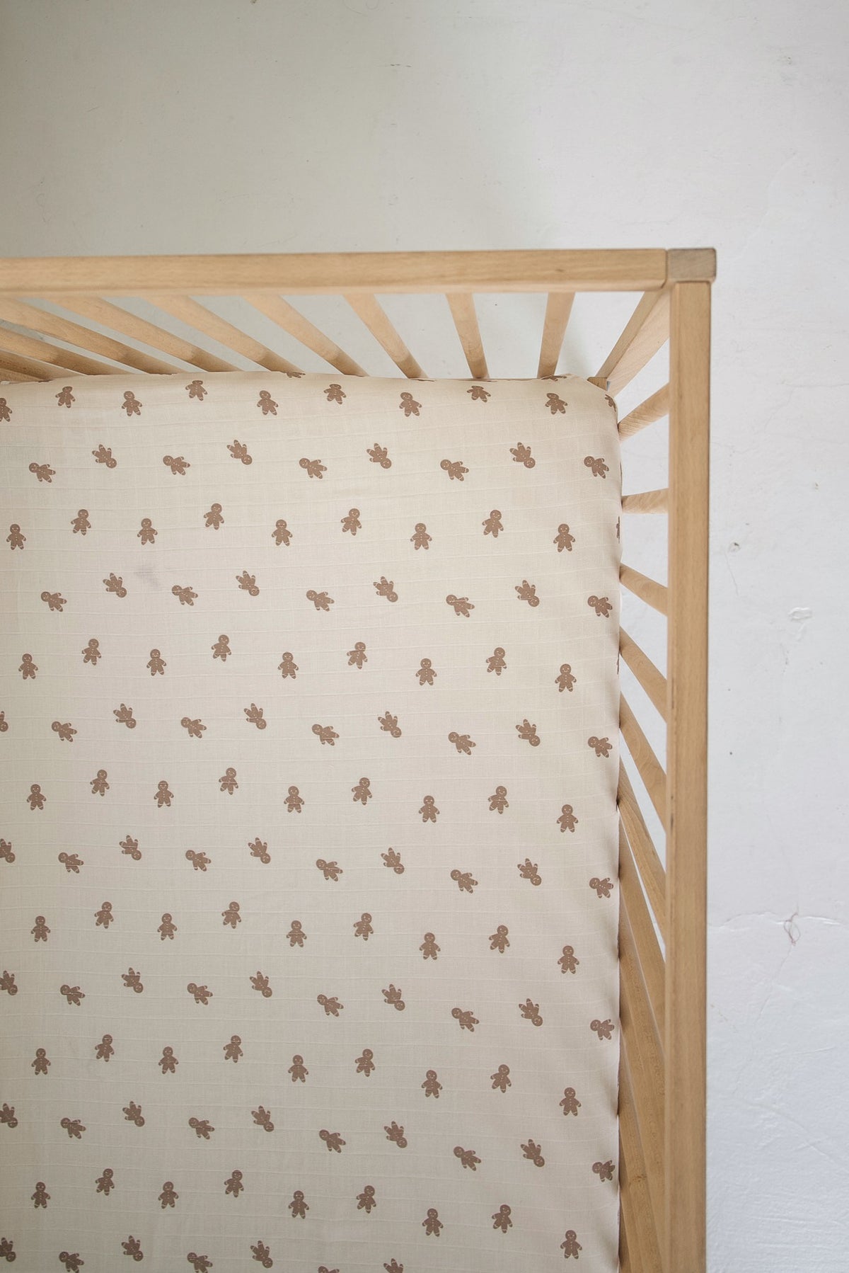 Forever French Baby Muslin Crib Sheet | Gingersnap with a repeating pattern of brown gingerbread men in a wooden crib.