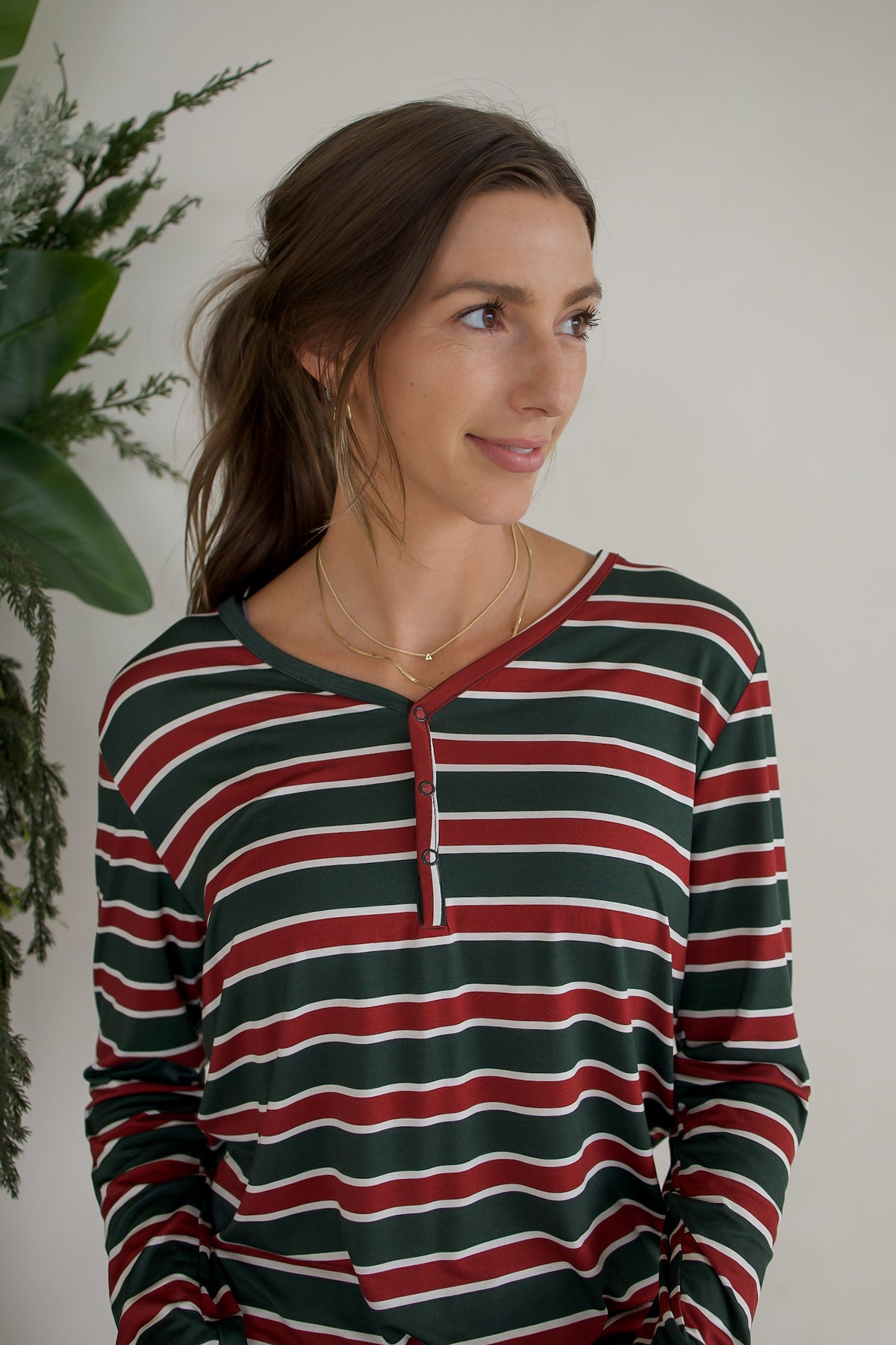 Woman wearing a Women’s Long Sleeve Bamboo Pajama | Holiday Stripe featuring a long-sleeve, henley-style design in red, dark green, and white stripes.
