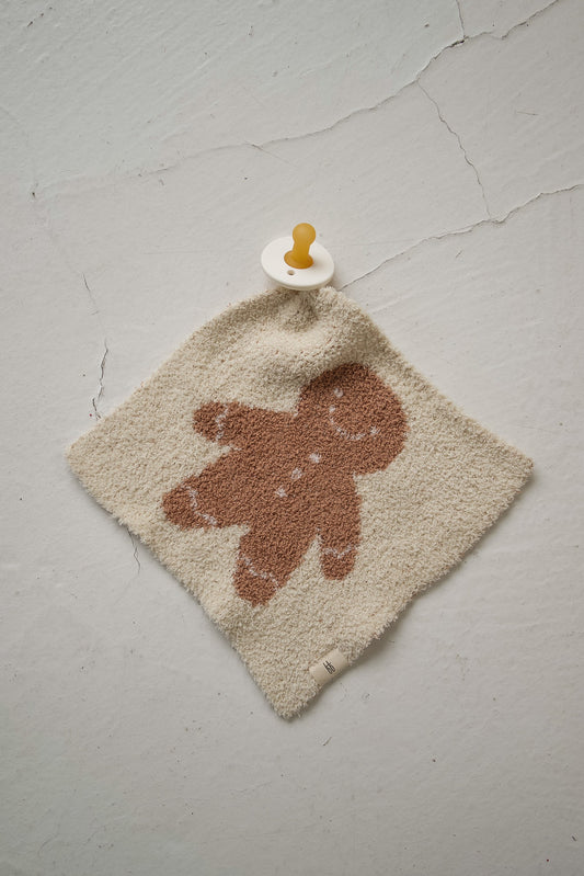 Forever french baby Gingersnap lovey, a square cream-colored microfiber feather yarn blanket featuring a brown gingerbread man with a silicone pacifier attached to the top corner.