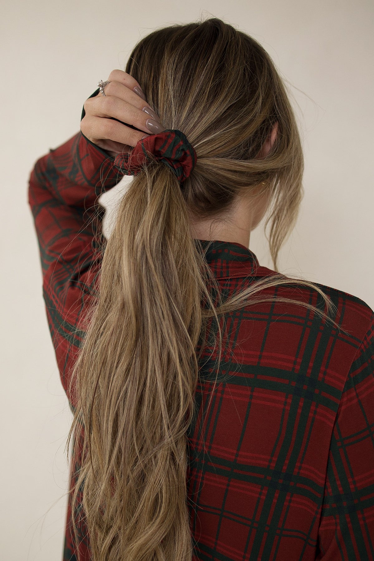 A person wearing a Christmas Plaid Scrunchie in a ponytail that matches their plaid shirt.
