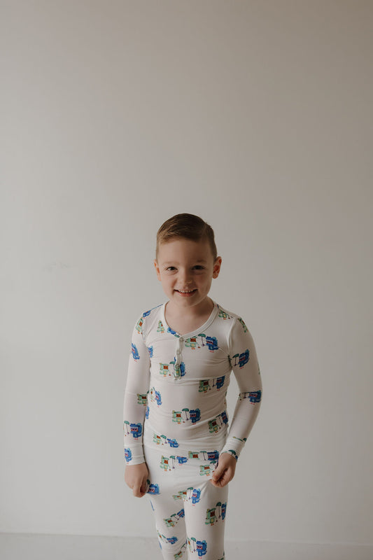 A young boy smiles against a white background, wearing forever french baby Bamboo Two Piece Pajamas | Charli's Monsters, cozy hypoallergenic kids' sleepwear featuring playful monster designs.