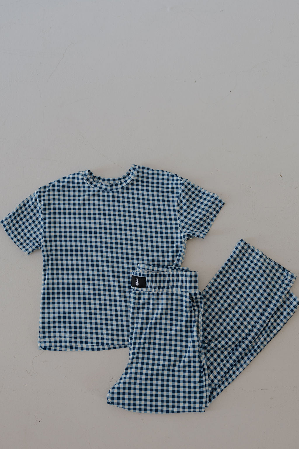 The forever french baby Child Boxy Tee Lounge Set in Blue Gingham, made from breathable bamboo fabric, features a short-sleeve top and matching pants with a blue and white checkered pattern, displayed on a light surface.