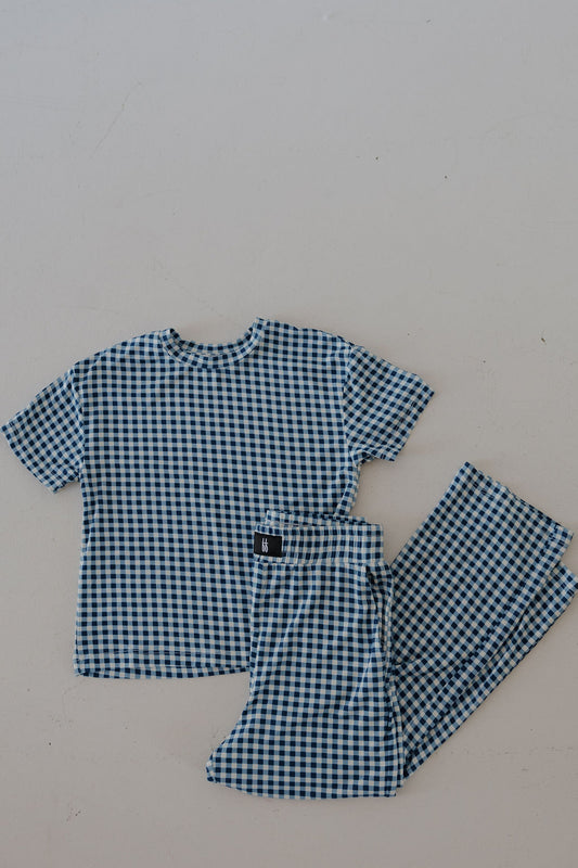 The forever french baby Child Boxy Tee Lounge Set in Blue Gingham, made from breathable bamboo fabric, features a short-sleeve top and matching pants with a blue and white checkered pattern, displayed on a light surface.