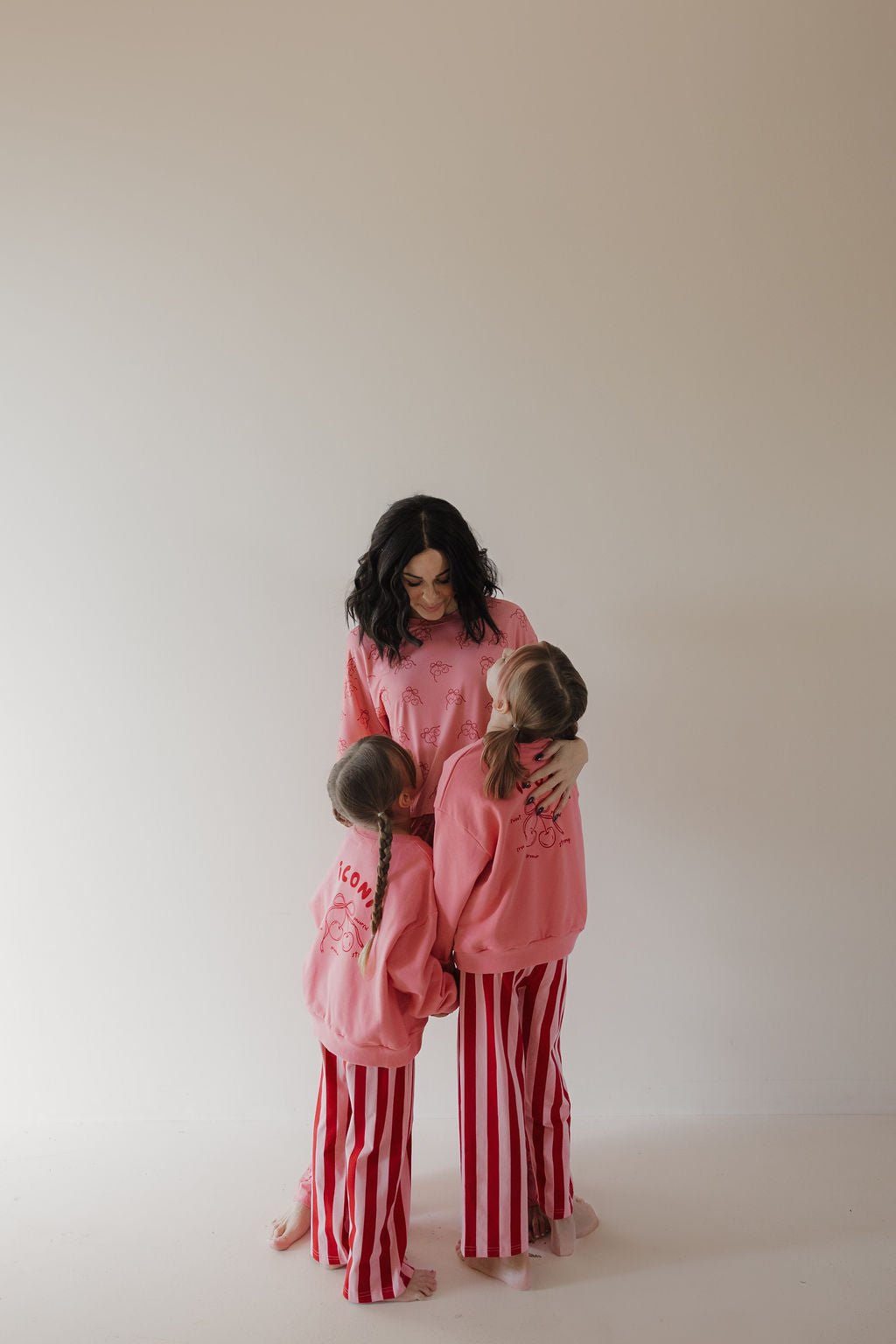 A woman and two kids in matching Minty Cherries Child Sweatshirt | Iconic Cherry pose together against a light background as the kids hug her.