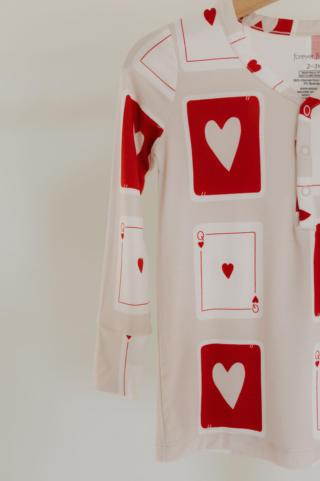 The "Love Day" Bamboo Two Piece Pajamas by forever french baby feature long sleeves and breathable fabric with a red hearts and "Q" pattern on cream, reflecting the Queen of Hearts from playing cards for stylish comfort.