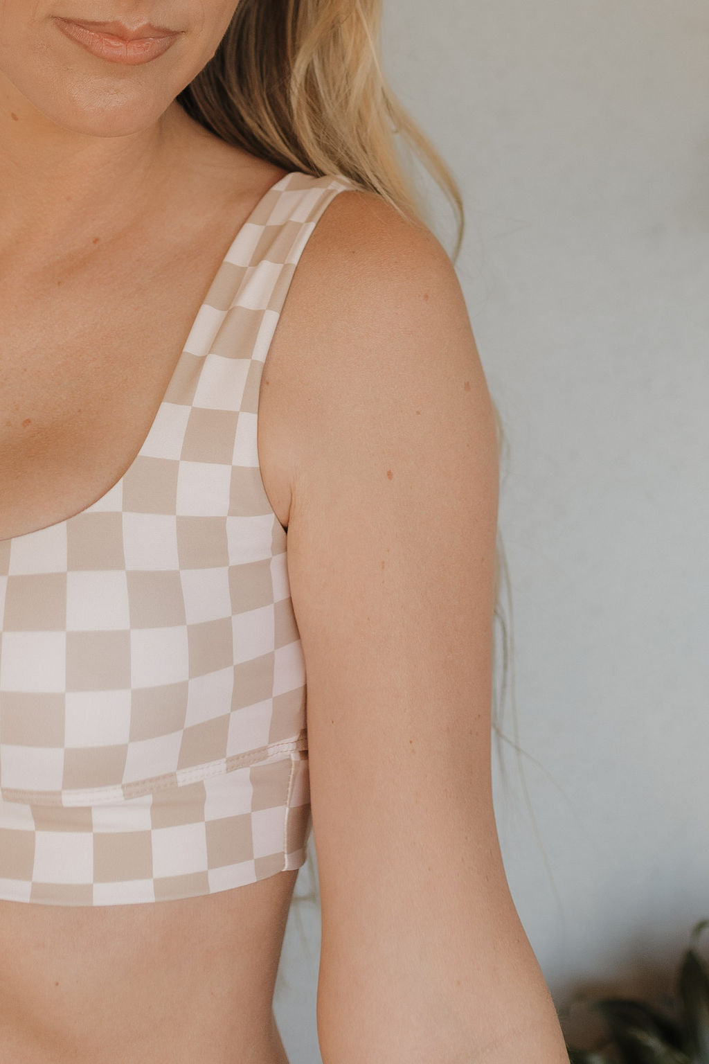 Close-up of a person with long blonde hair wearing a sleeveless beige and white checkered top, echoing the Women's Two Piece Swimsuit | Coastline from forever french baby. The focus is on the upper body, set against a neutral background with soft lighting.