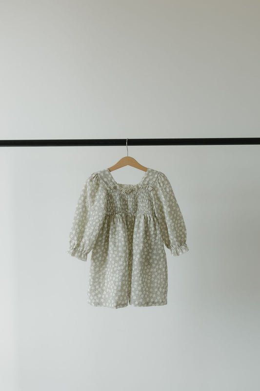 A Child Dress | French Gray Floral from forever french baby, featuring a hypo-allergenic design with a gathered bodice and flowy silhouette, hangs on a simple wooden hanger against a plain white background.